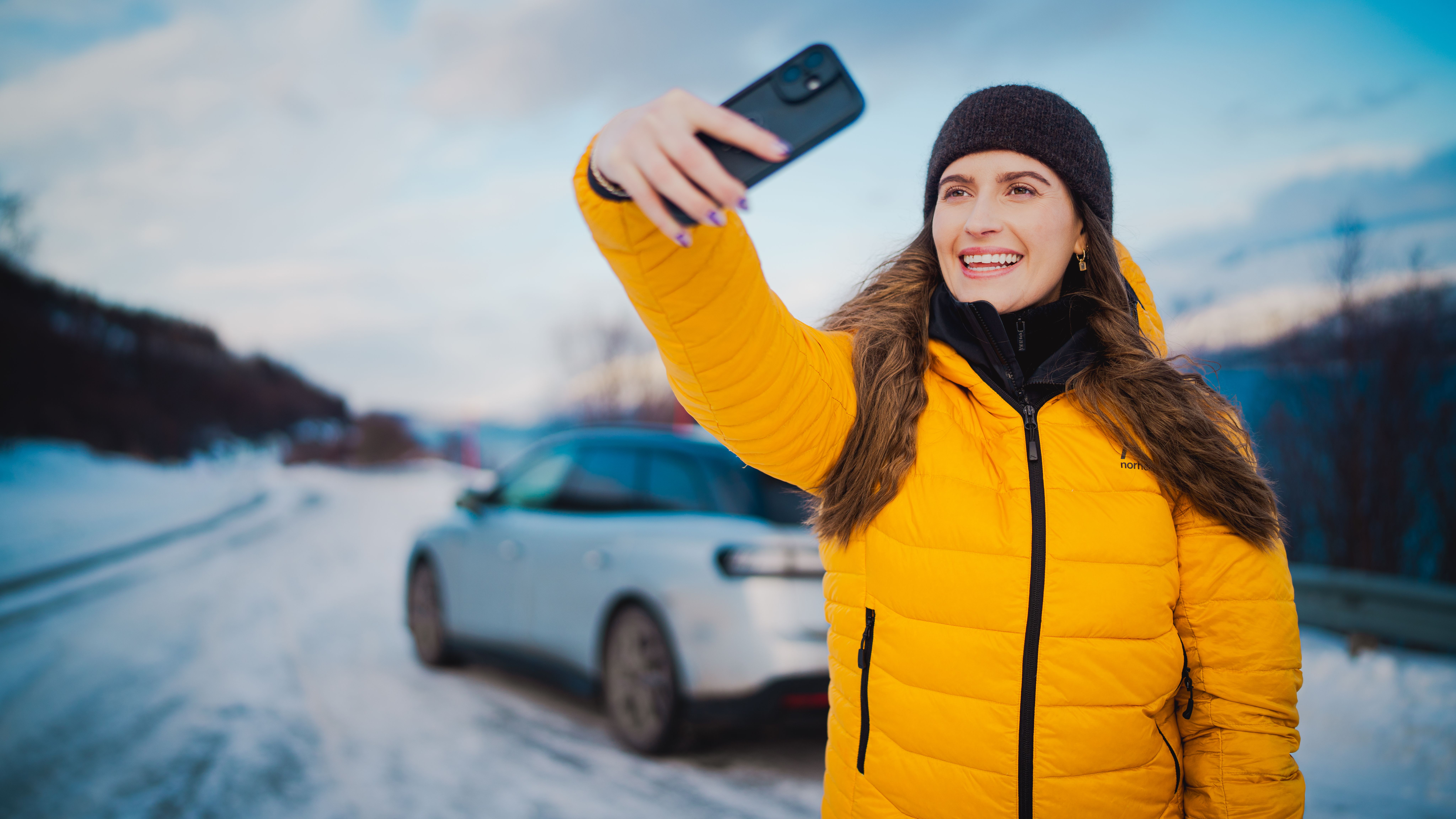 A woman taking a selfie on a road trip in winter.