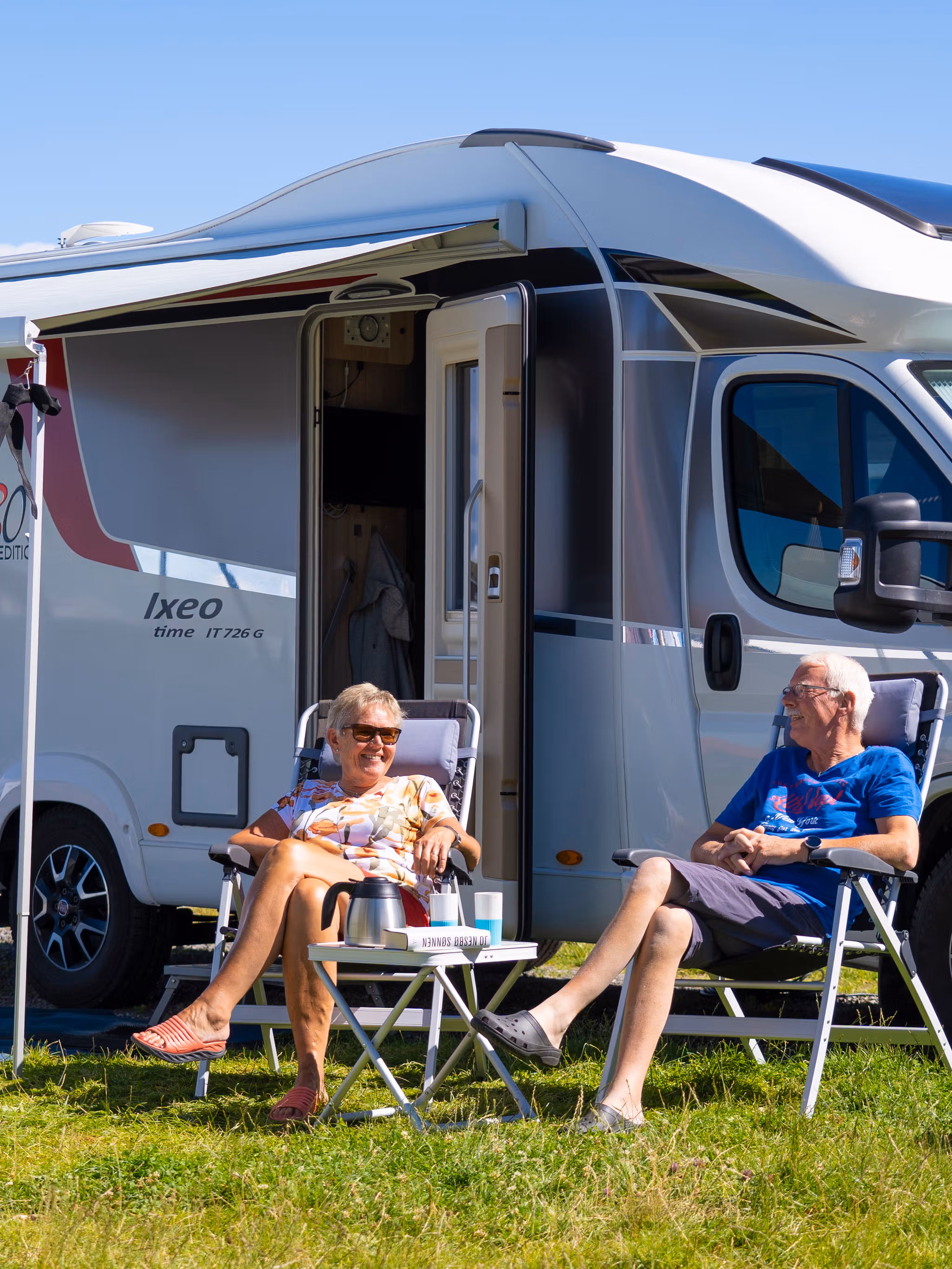 Two people in front of a motorhome on camping