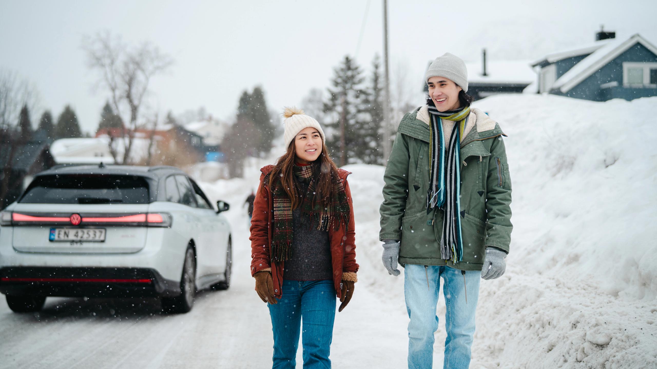 Two tourists walking on the left side of the road.