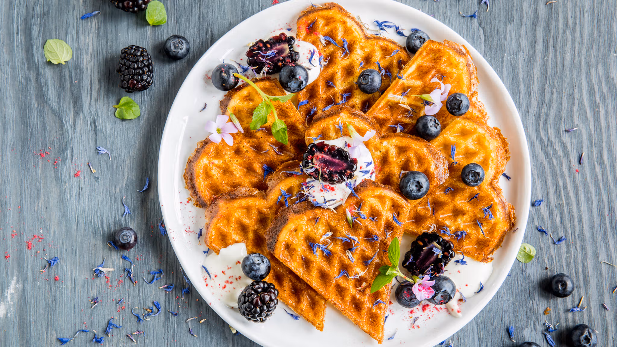 A plate of waffles with sour cream and berries