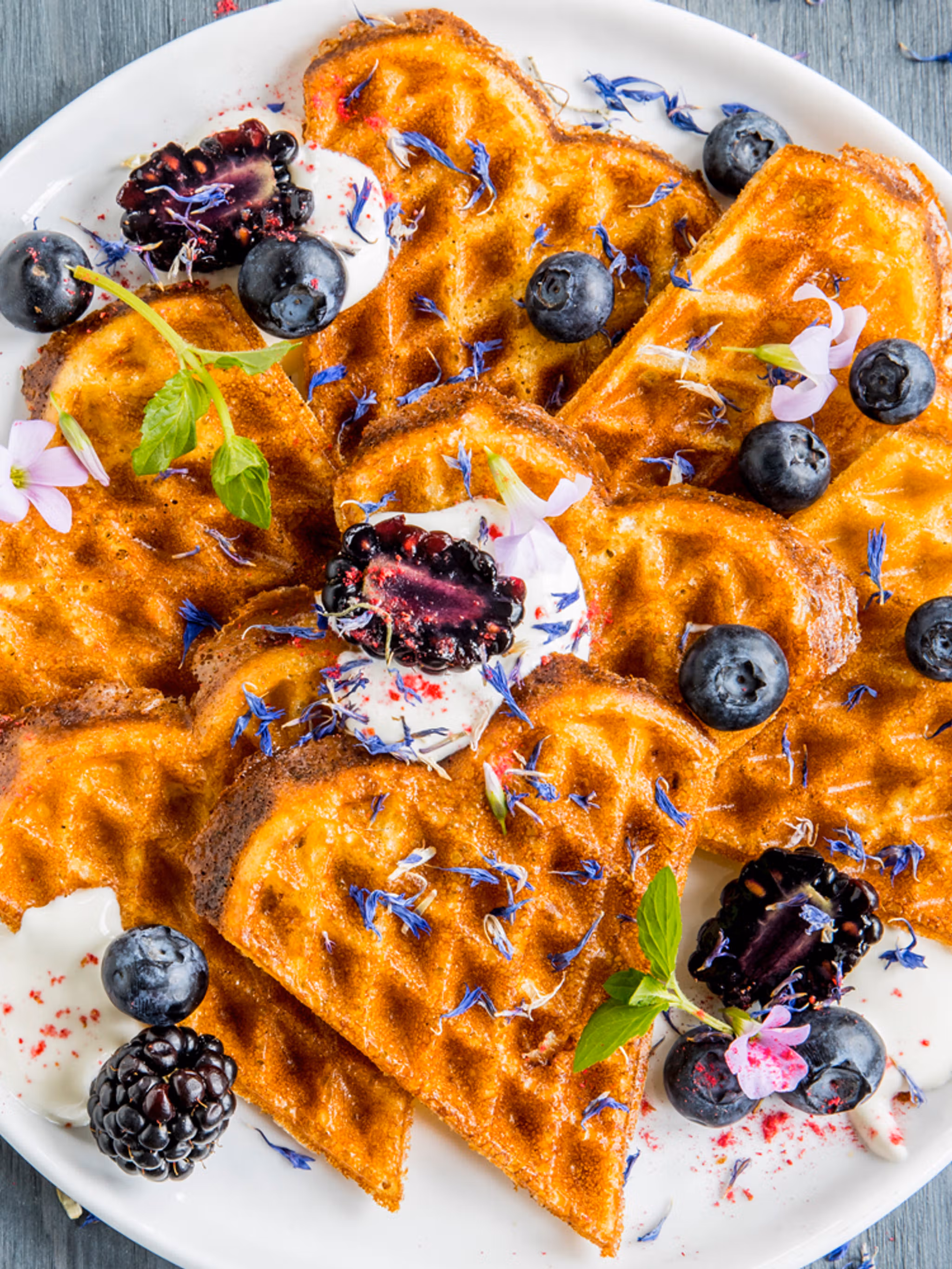 A plate of waffles with sour cream and berries