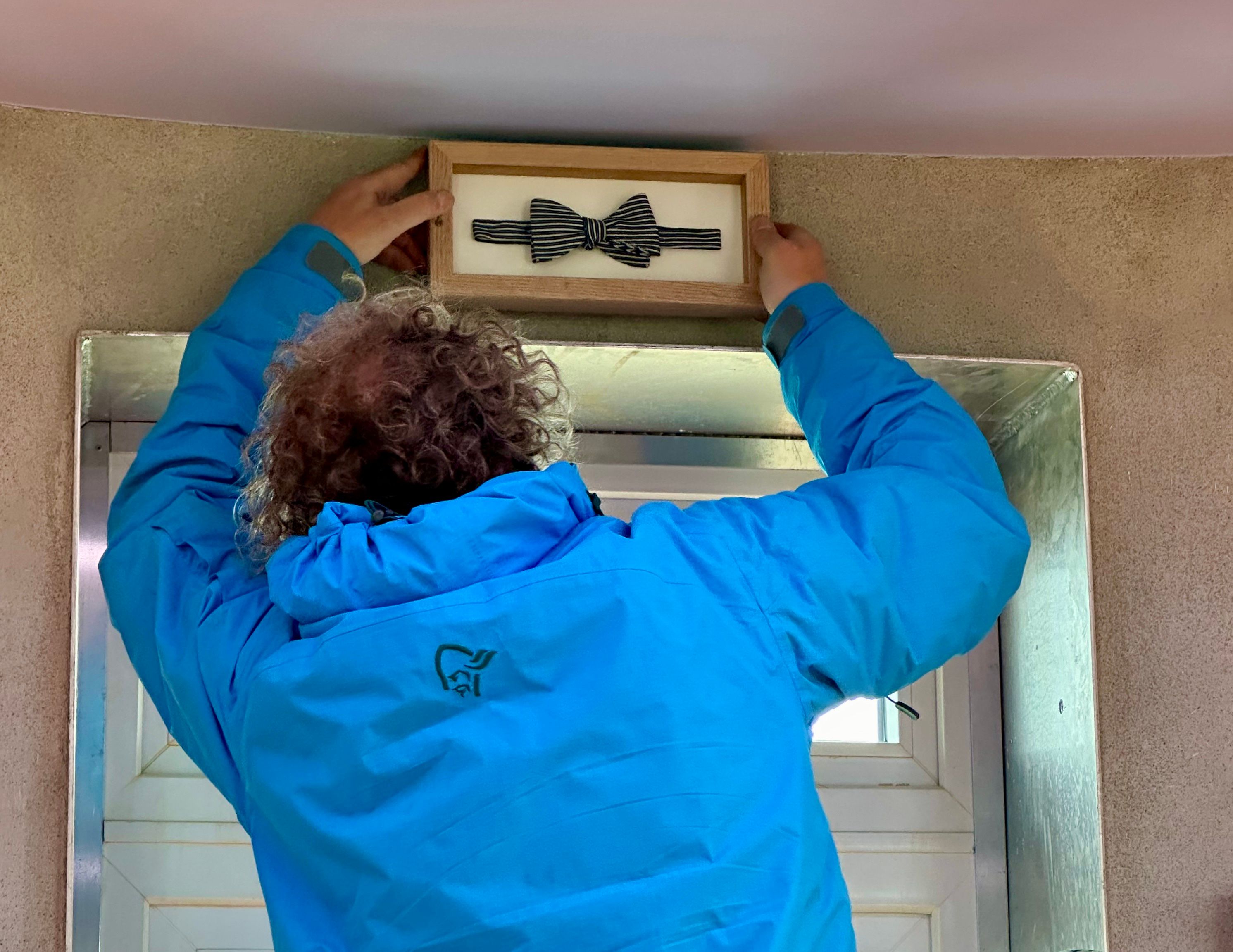 Martin Otterbeck putting up a Per Fugelli's bow tie on the wall inside Ettertanken at Røst