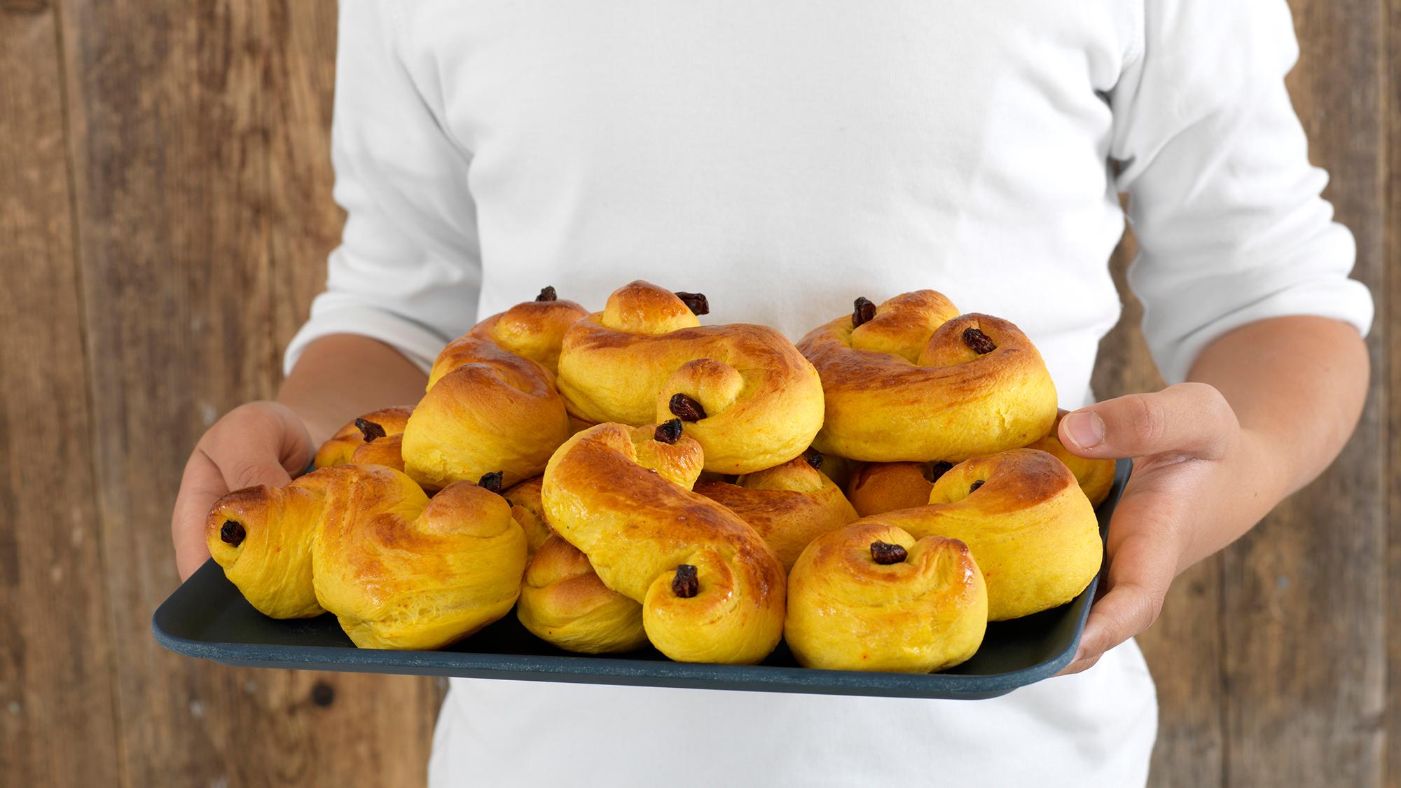 A person holding a plate with saffron buns in Norway