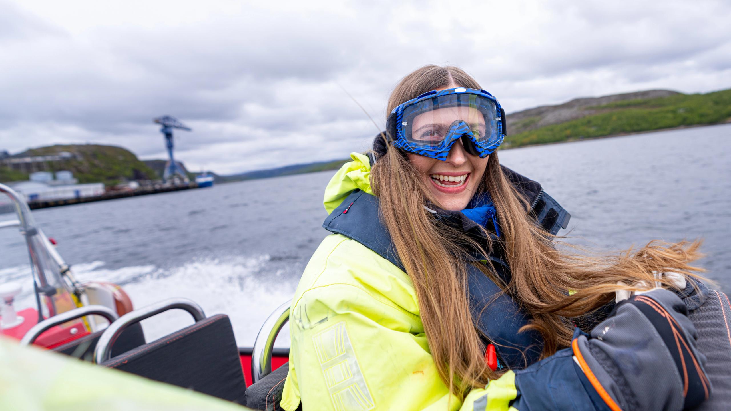 En glad kvinne kjører ribbåt utenfor Kirkenes, Nord-Norge.