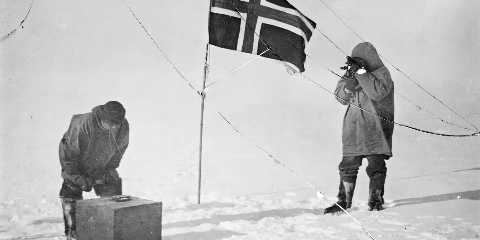 Roald Amundsen and Helmer Hanssen next to a Norwegian flag at the South Pole in 1911