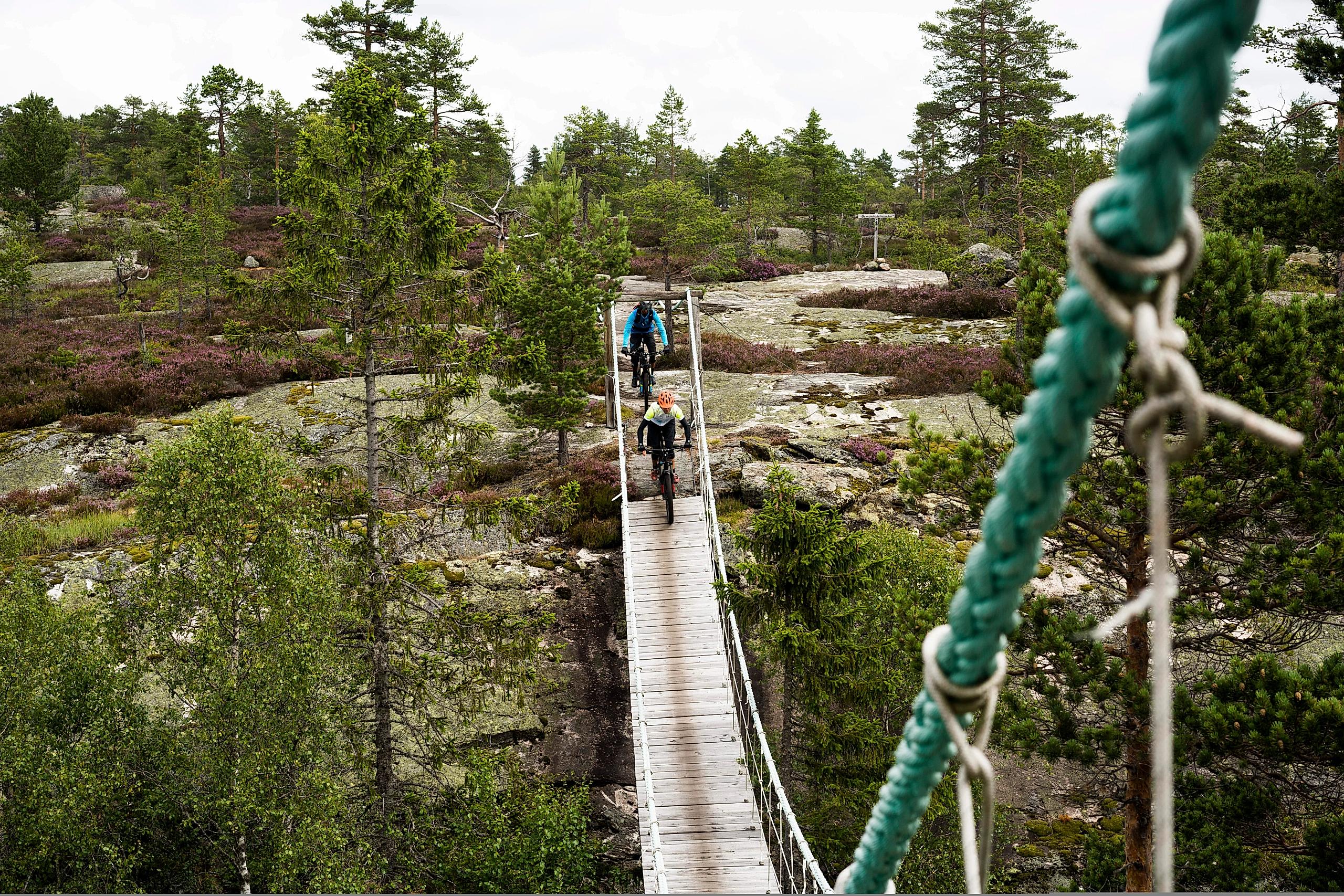 Two people mountain biking across a bridge in Nissedal in Telemark, Eastern Norway