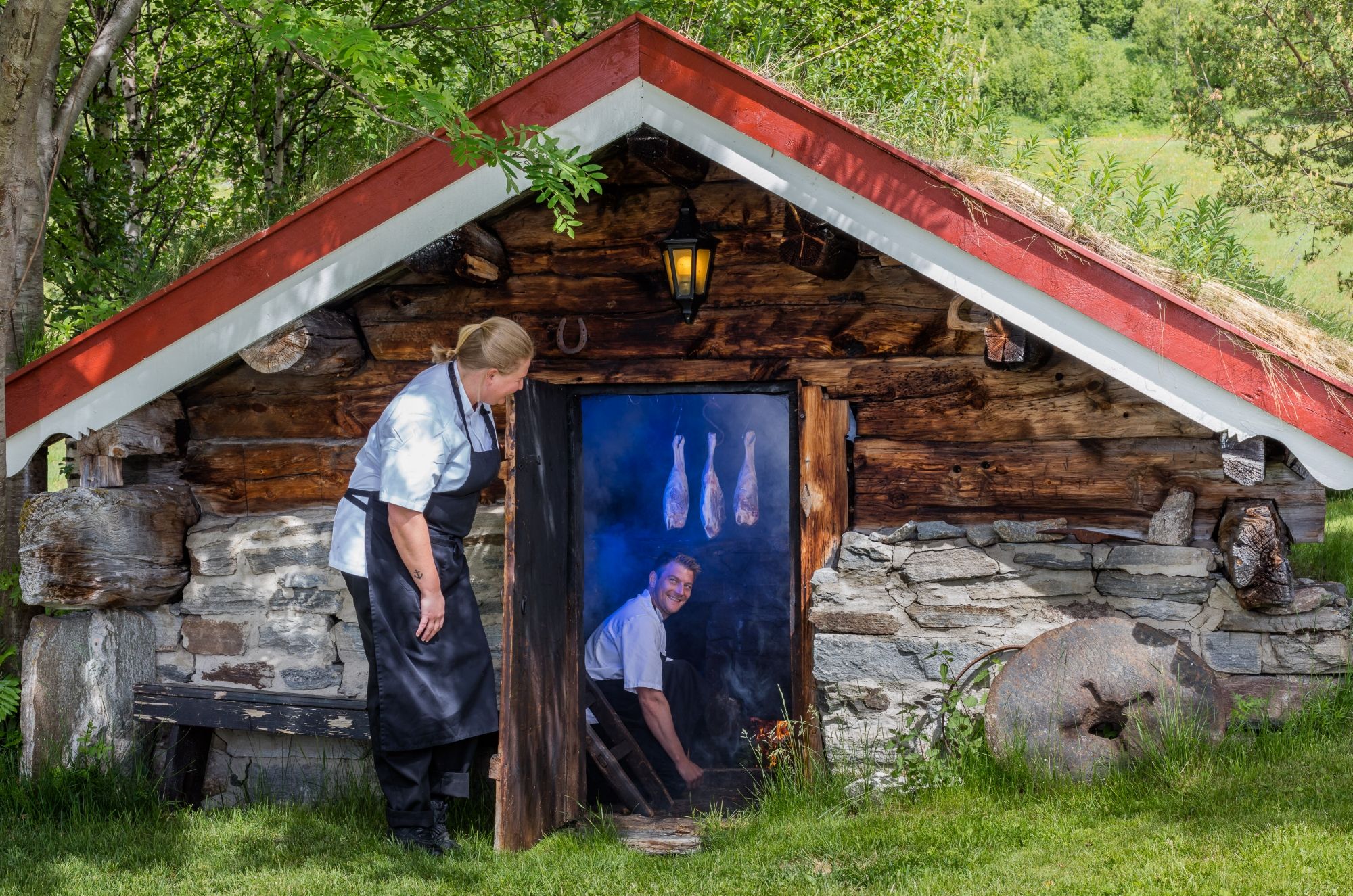 En mann lager røkt lammelår i en røykbadstu på Bortistu gjestegard i Oppdal i Trøndelag