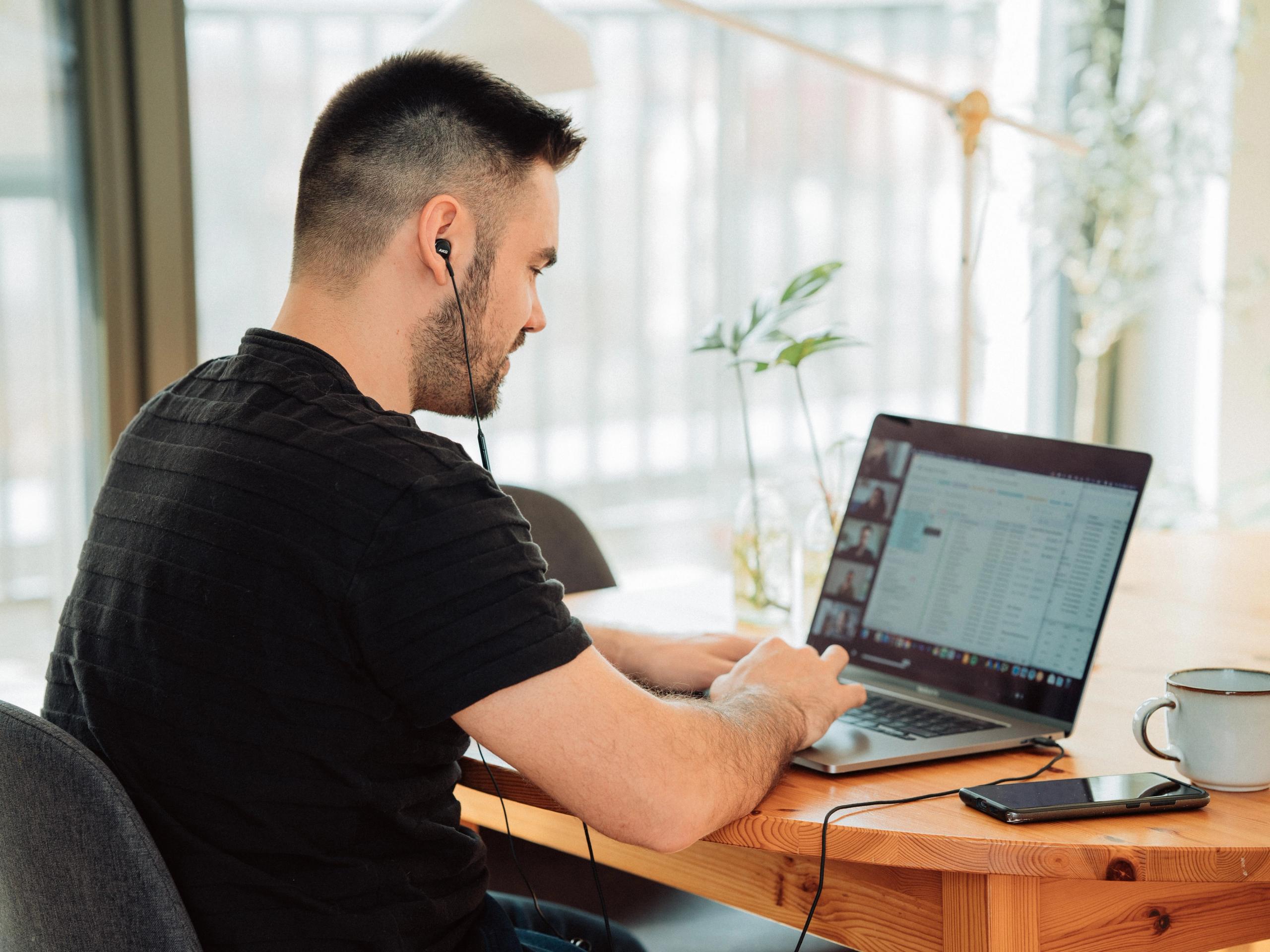 A young man in a black T-shirt in a conference meeting on his laptop