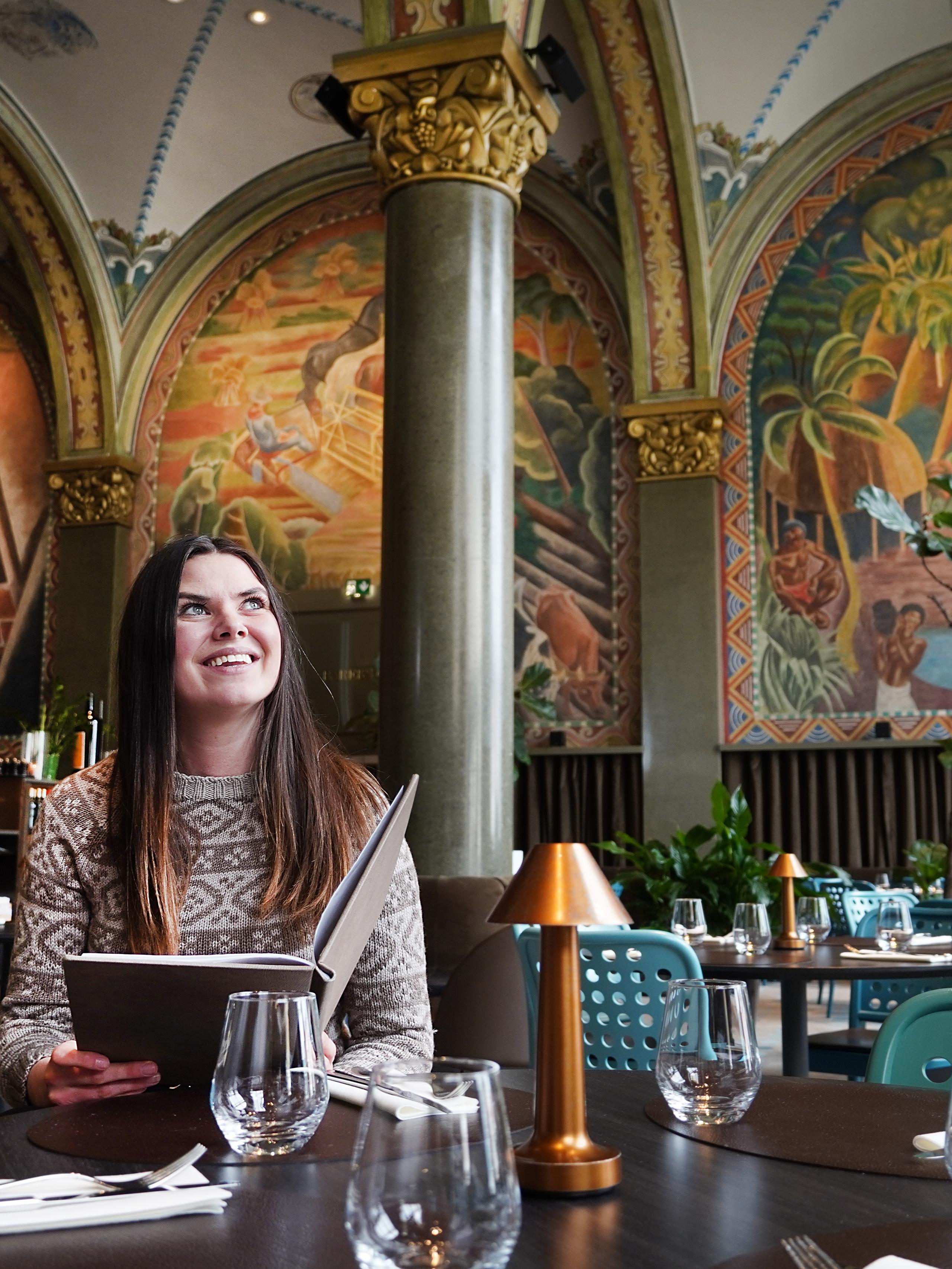 En dame sitter i restauranten Frescohallen - Bergen Børs Hotel