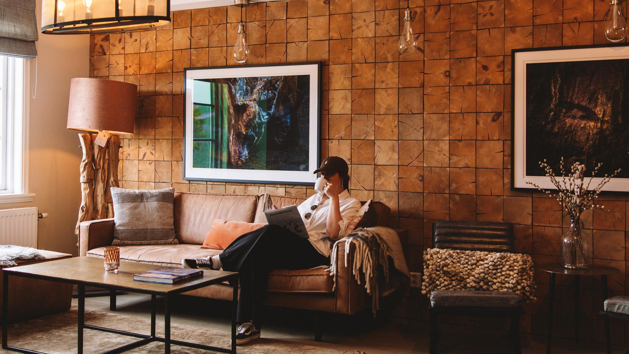 A woman sitting inside the living room at Skåbu mountain hotel in Skåbu.