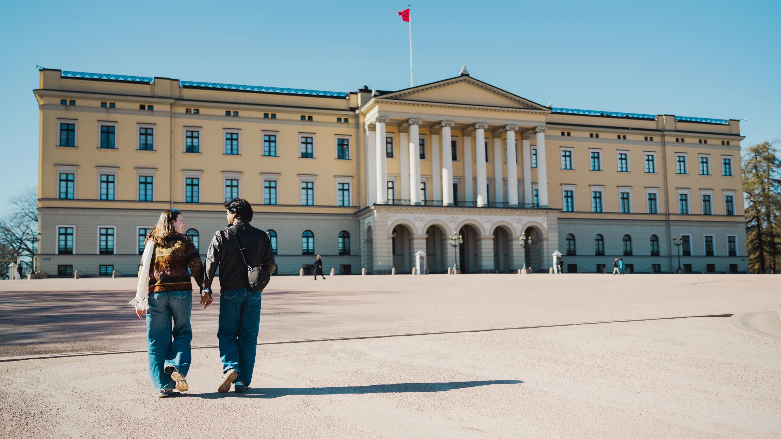 A couple walking in front of the royal castle.