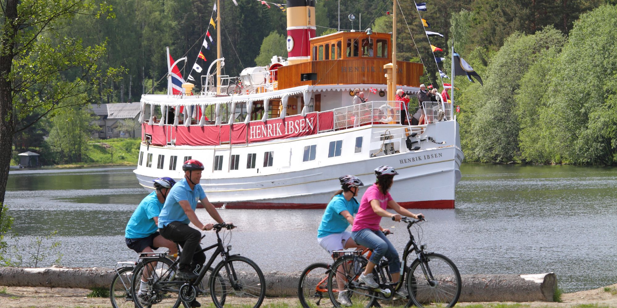 Des cyclistes dépassent un bateau navigant sur le canal, sur la véloroute nationale du canal du Telemark, en Norvège de l’Est