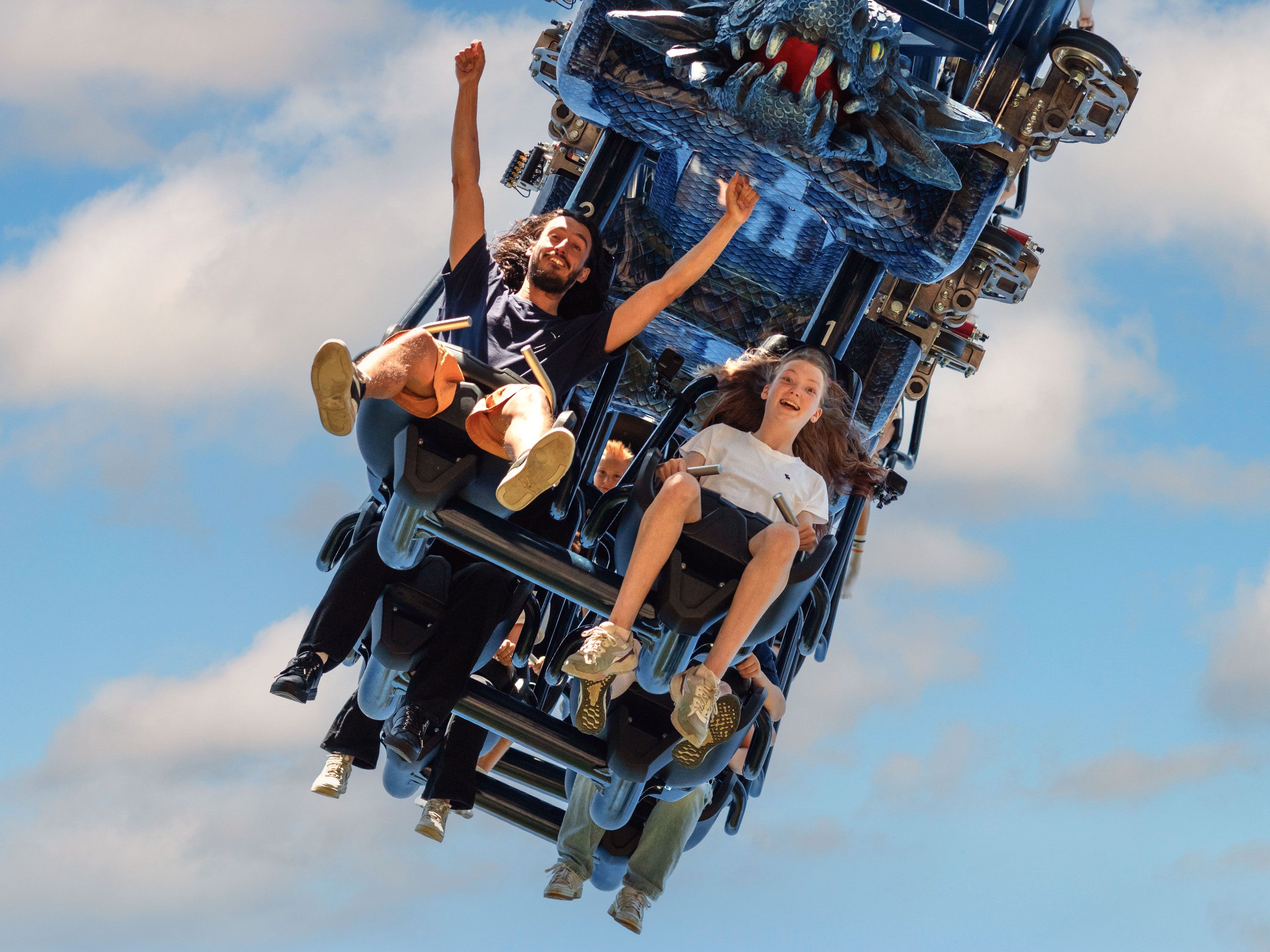 Several riders experience a roller coaster, with their arms raised and expressions of excitement.