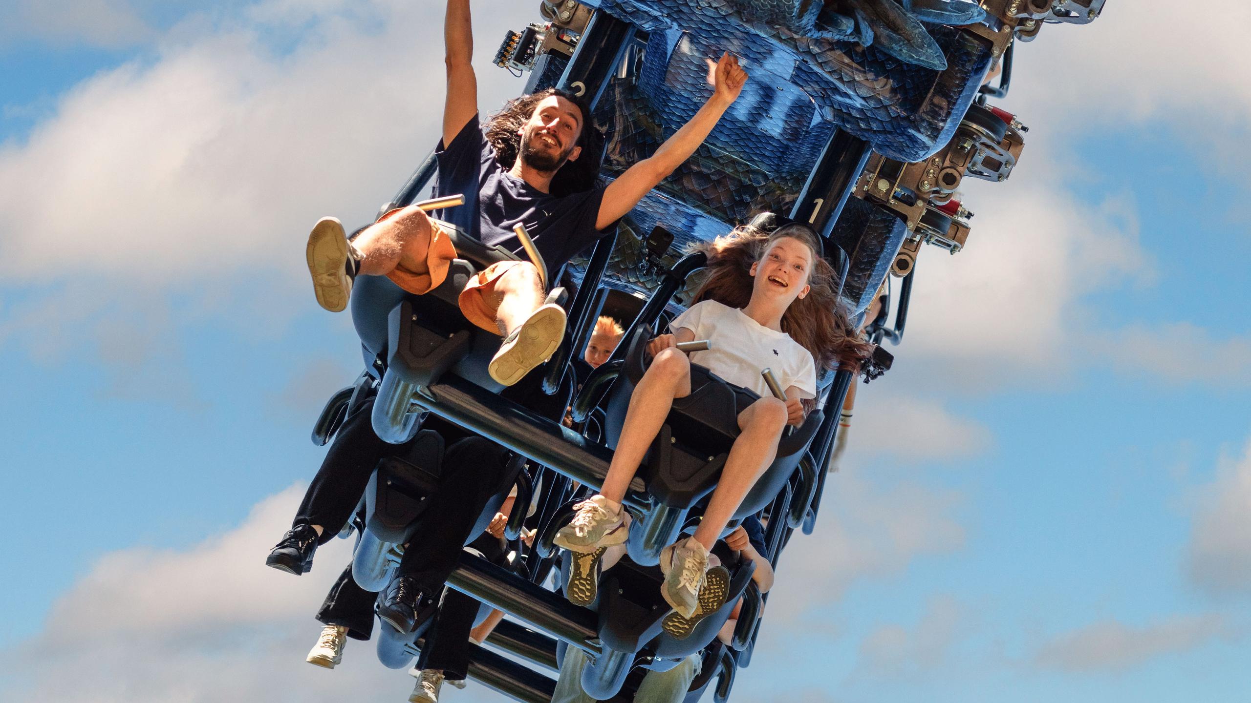 Several riders experience a roller coaster, with their arms raised and expressions of excitement.