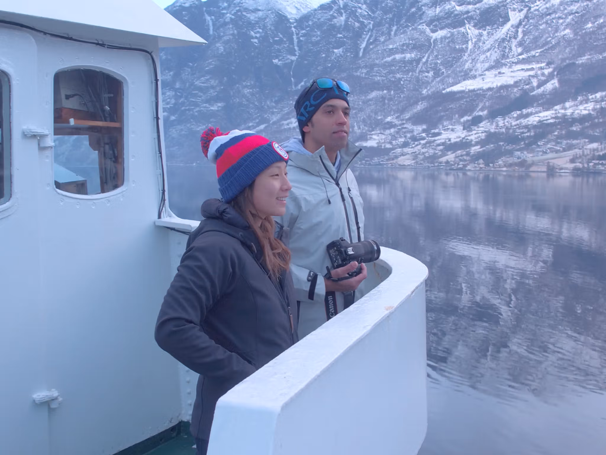 To personer står på dekk og nyter utsikten over Nærøyfjorden om vinteren