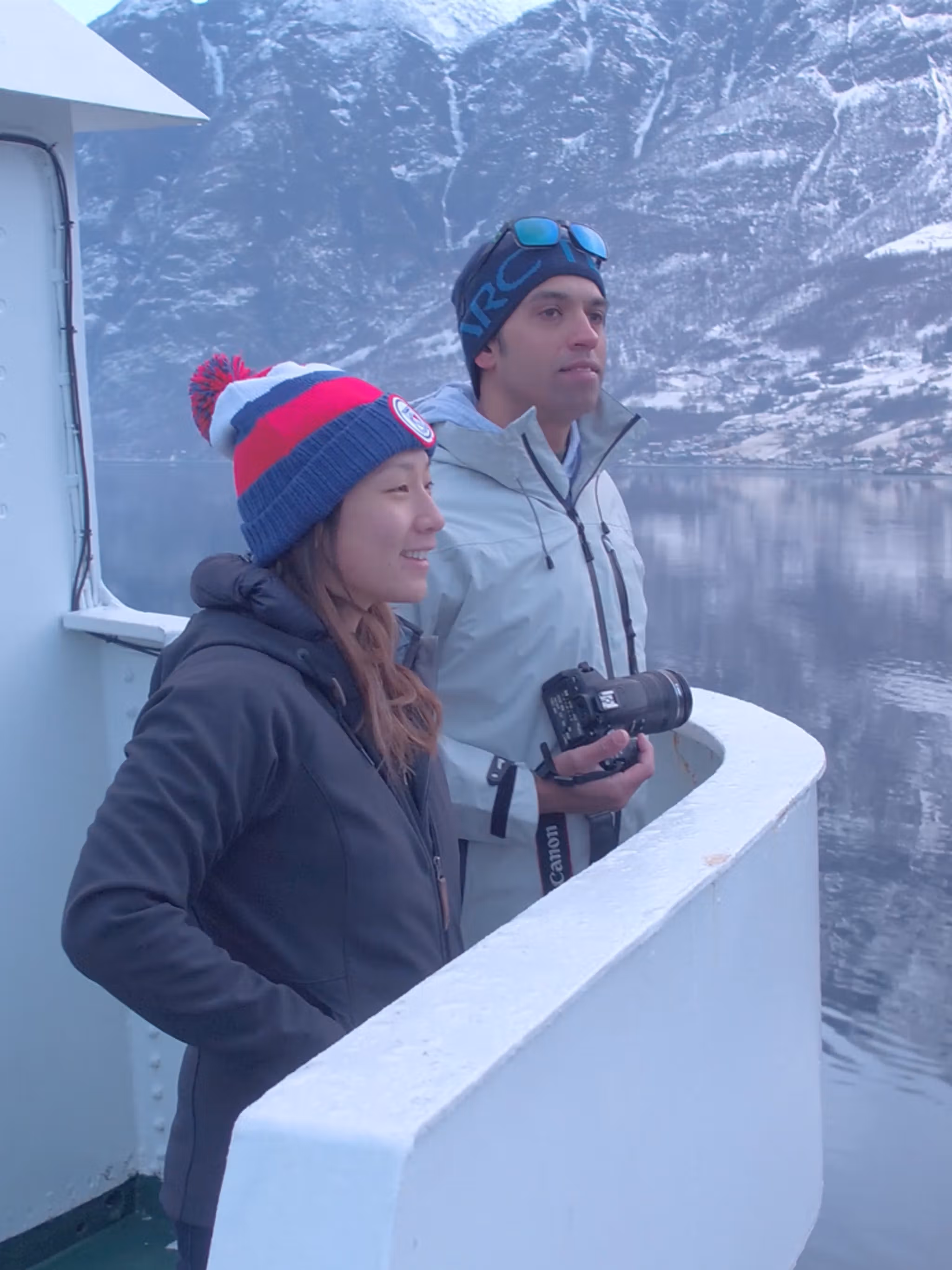 Two people standing on a boat enjoying the view of the Nærøyfjord in winter