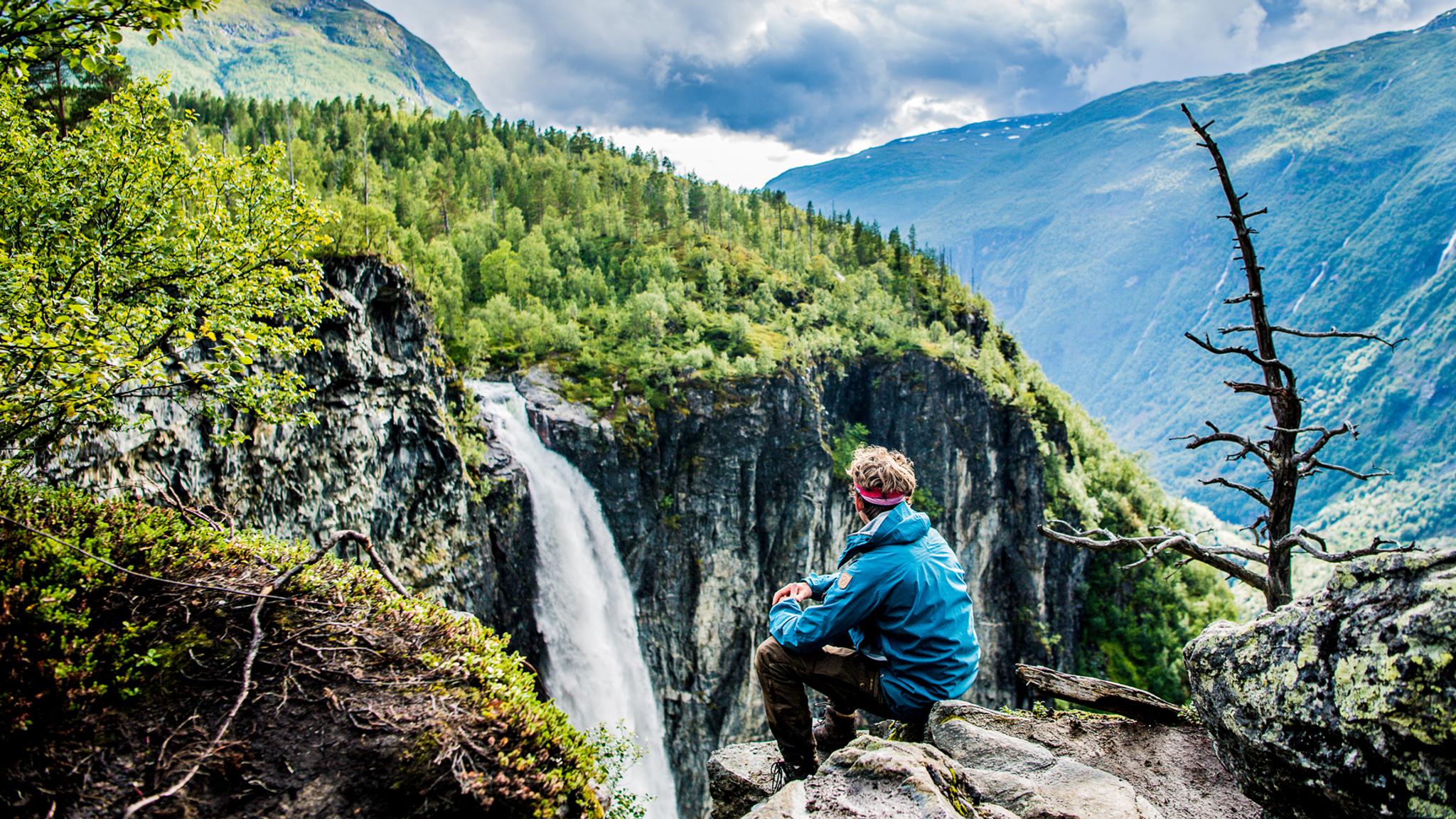 Escursionista ammira la vista della cascata Vettisfossen a Utladalen sui monti Jotunheimen, Norvegia