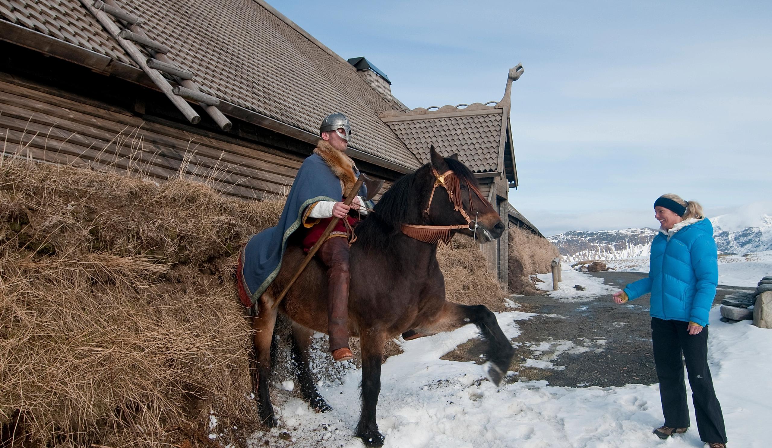 En viking til hest poserer for besøkende på Lofotr vikingmuseum i Nord-Norge