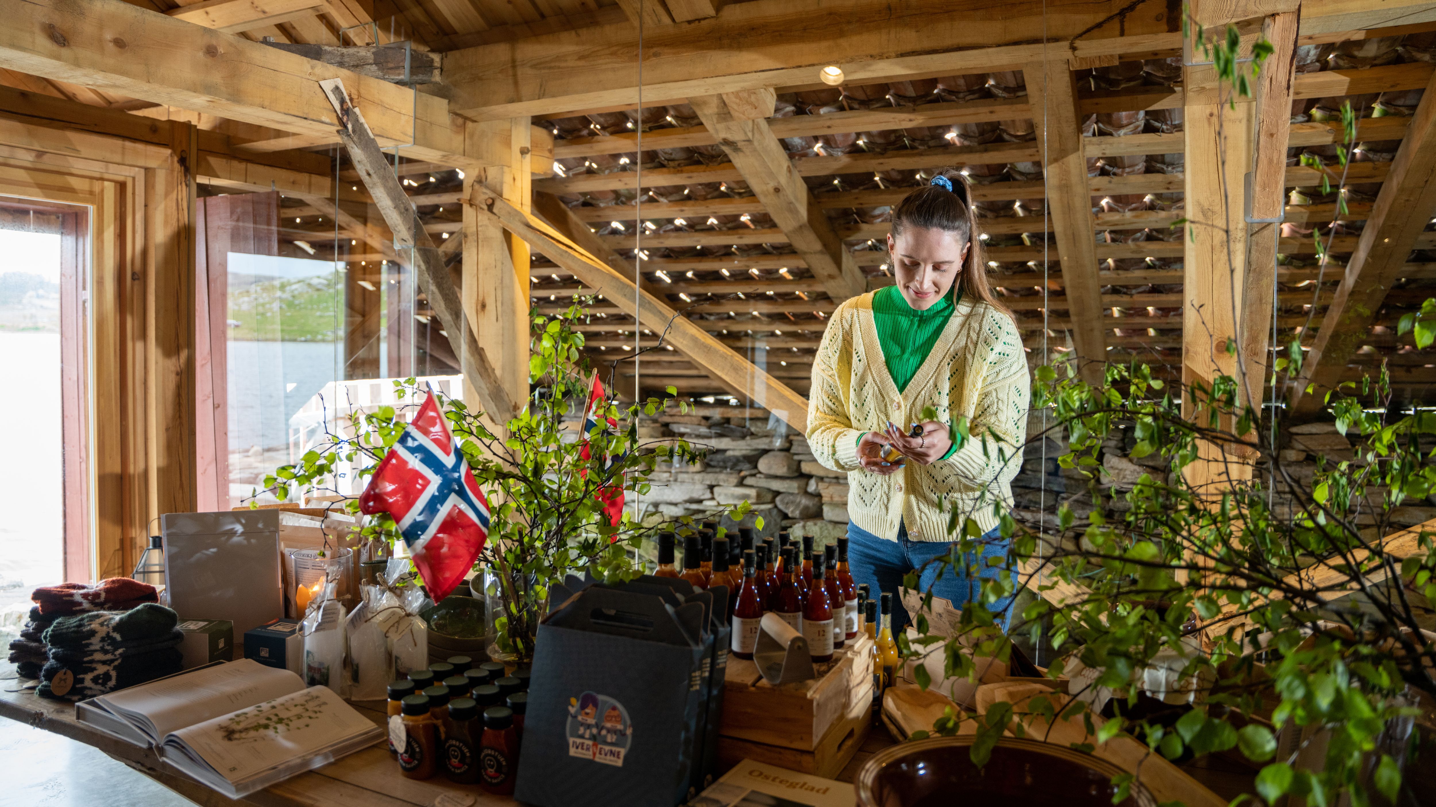 A woman looking at local products at a farm shop at Ulstein farm in the Stavanger Region, Fjord Norway.