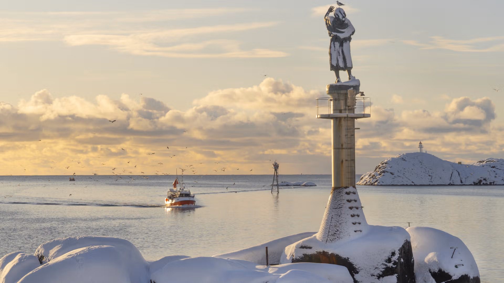 Skrei fishing boat by Fiskarkona statue in Lofoten