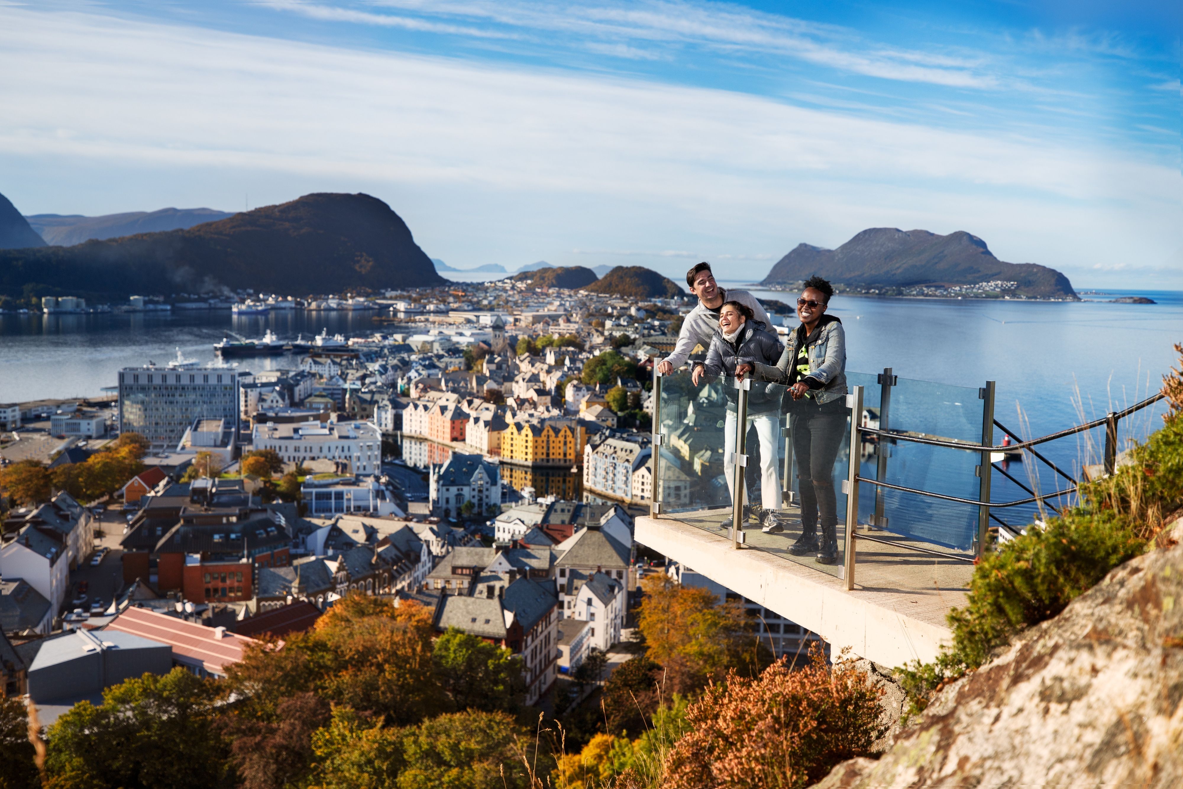 Three friends standing at a viewpoint above the city of Ålesund in Fjord Norway