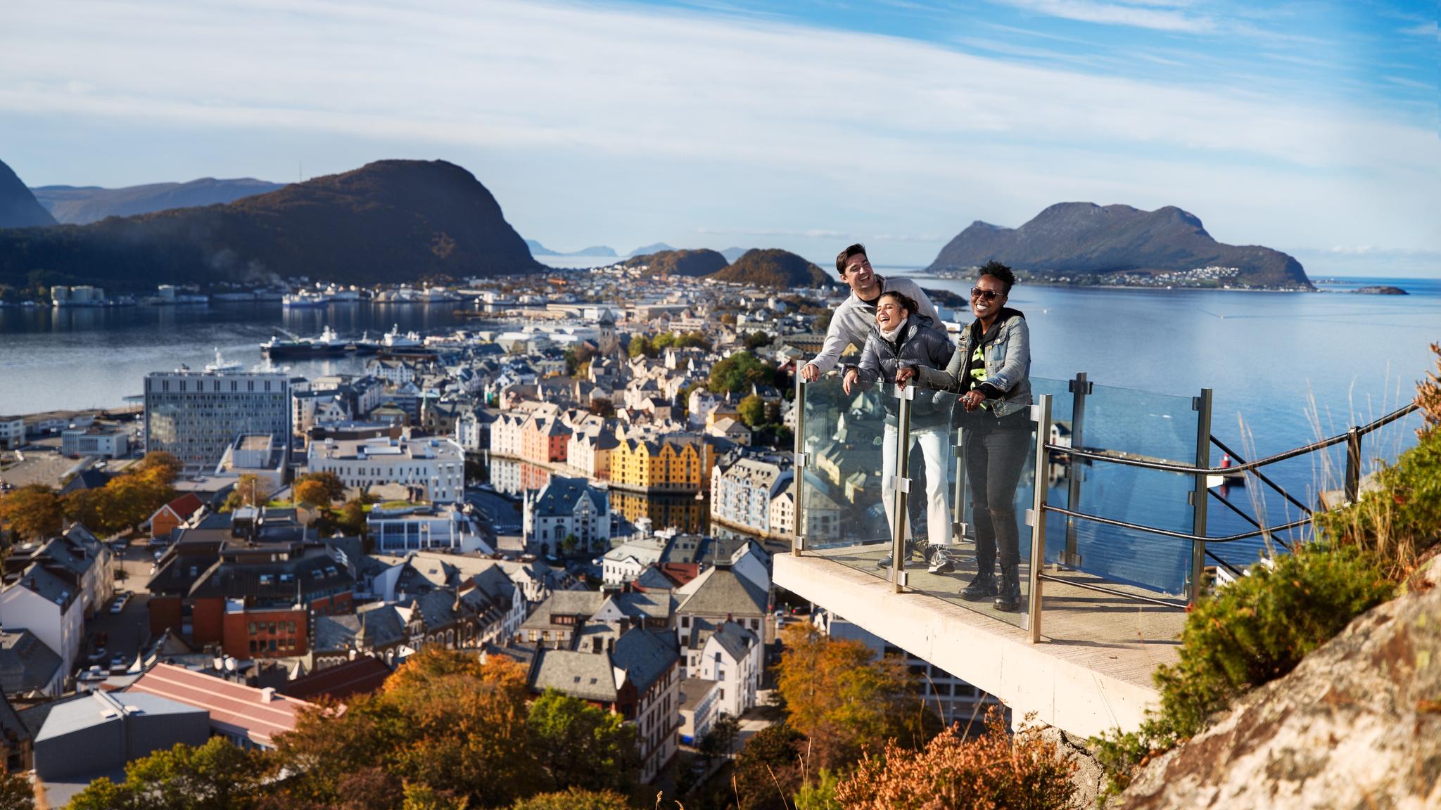 Three friends standing at a viewpoint above the city of Ålesund in Fjord Norway