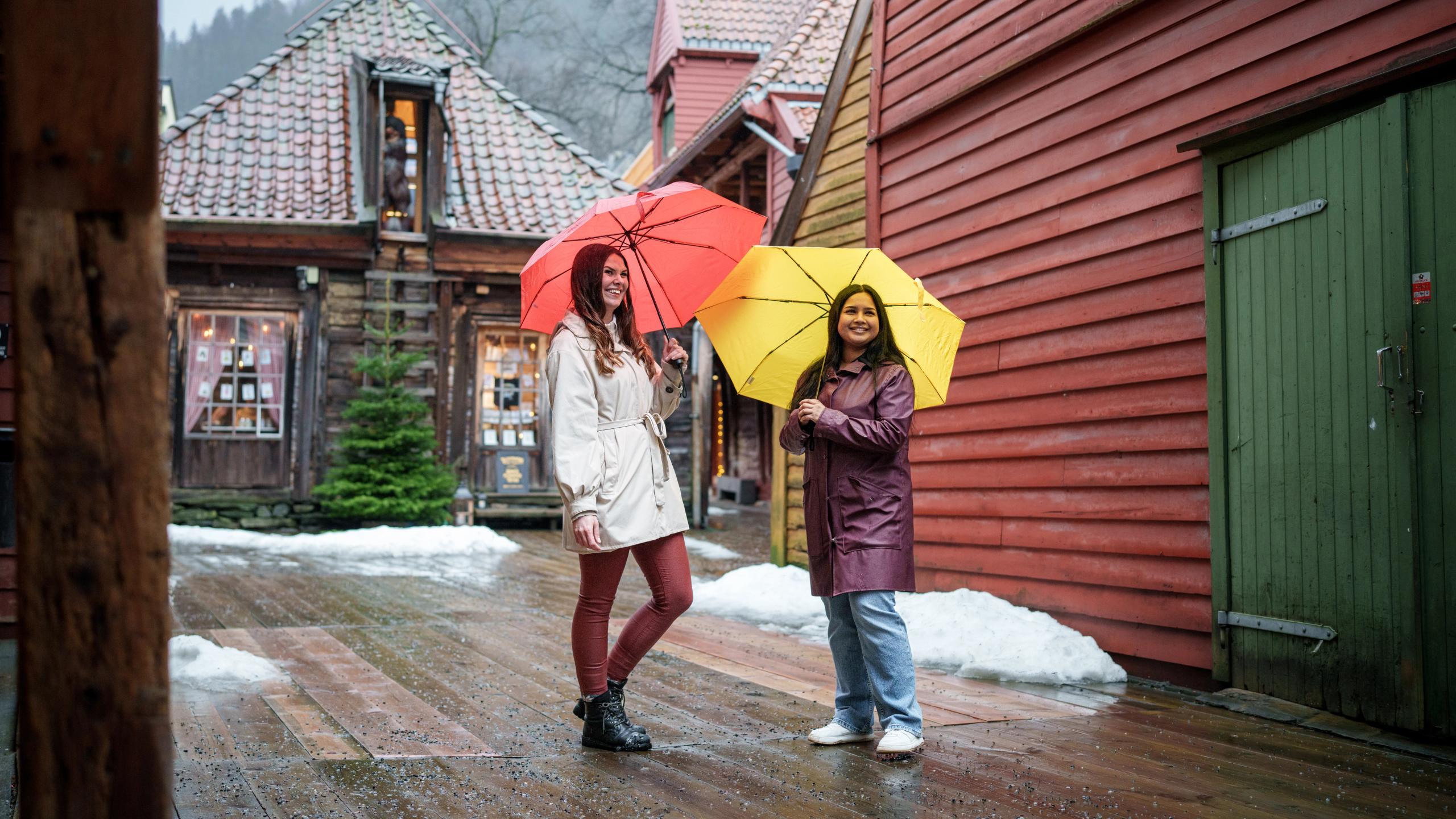 To jenter med paraply på insiden av Bryggen i Bergen