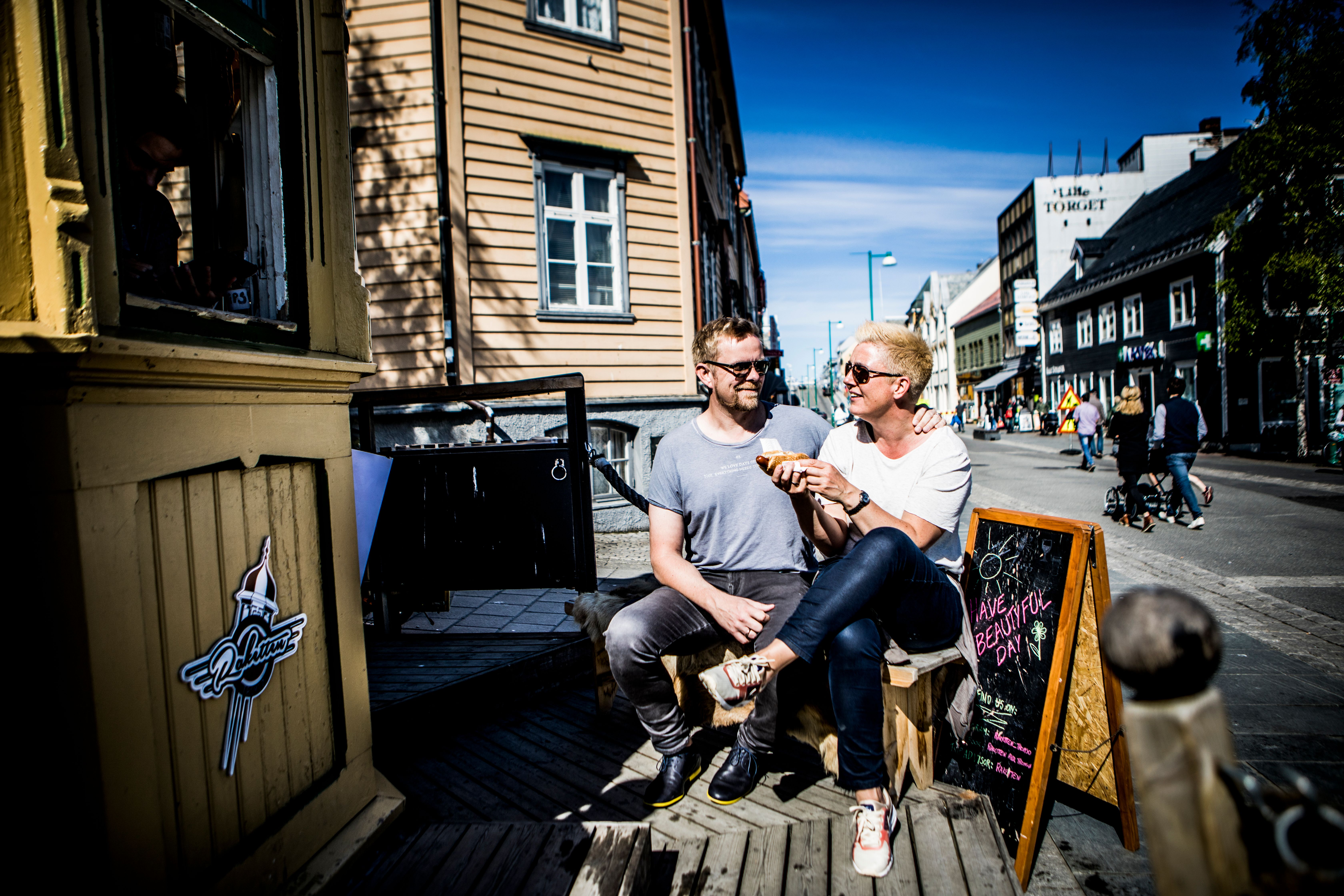 Two people enjoying hot dogs at  the kiosk Raketten Bar & Pølse in Tromsø in Northern Norway