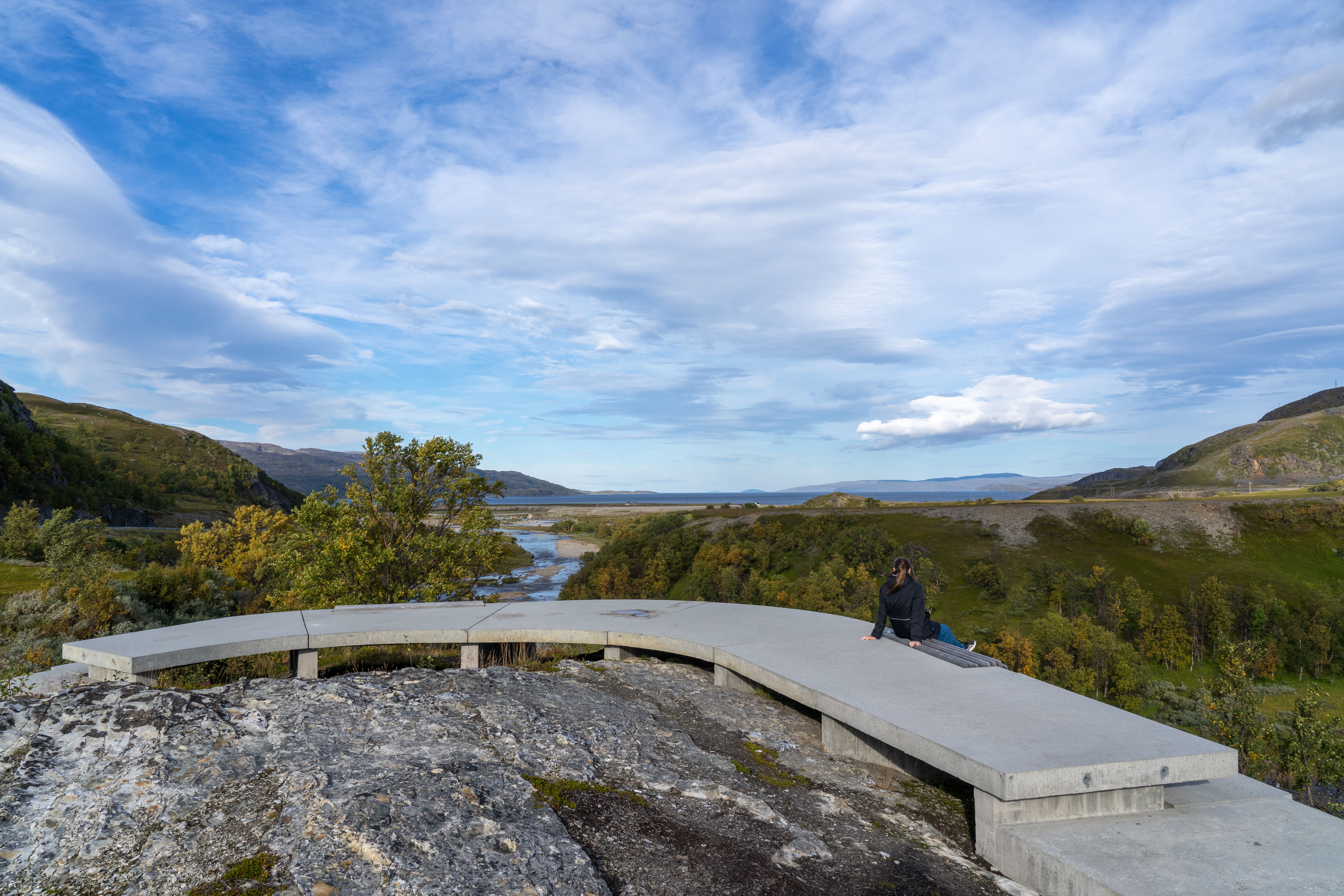 A woman sitting on a bench at the viewpoint of Storberget