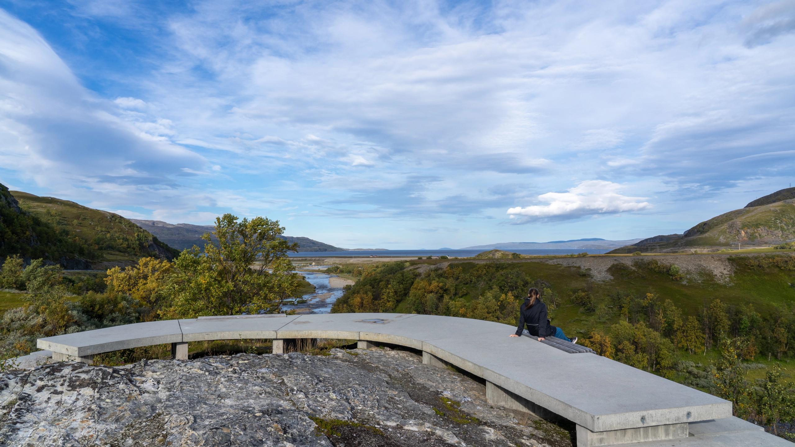 A woman sitting on a bench at the viewpoint of Storberget