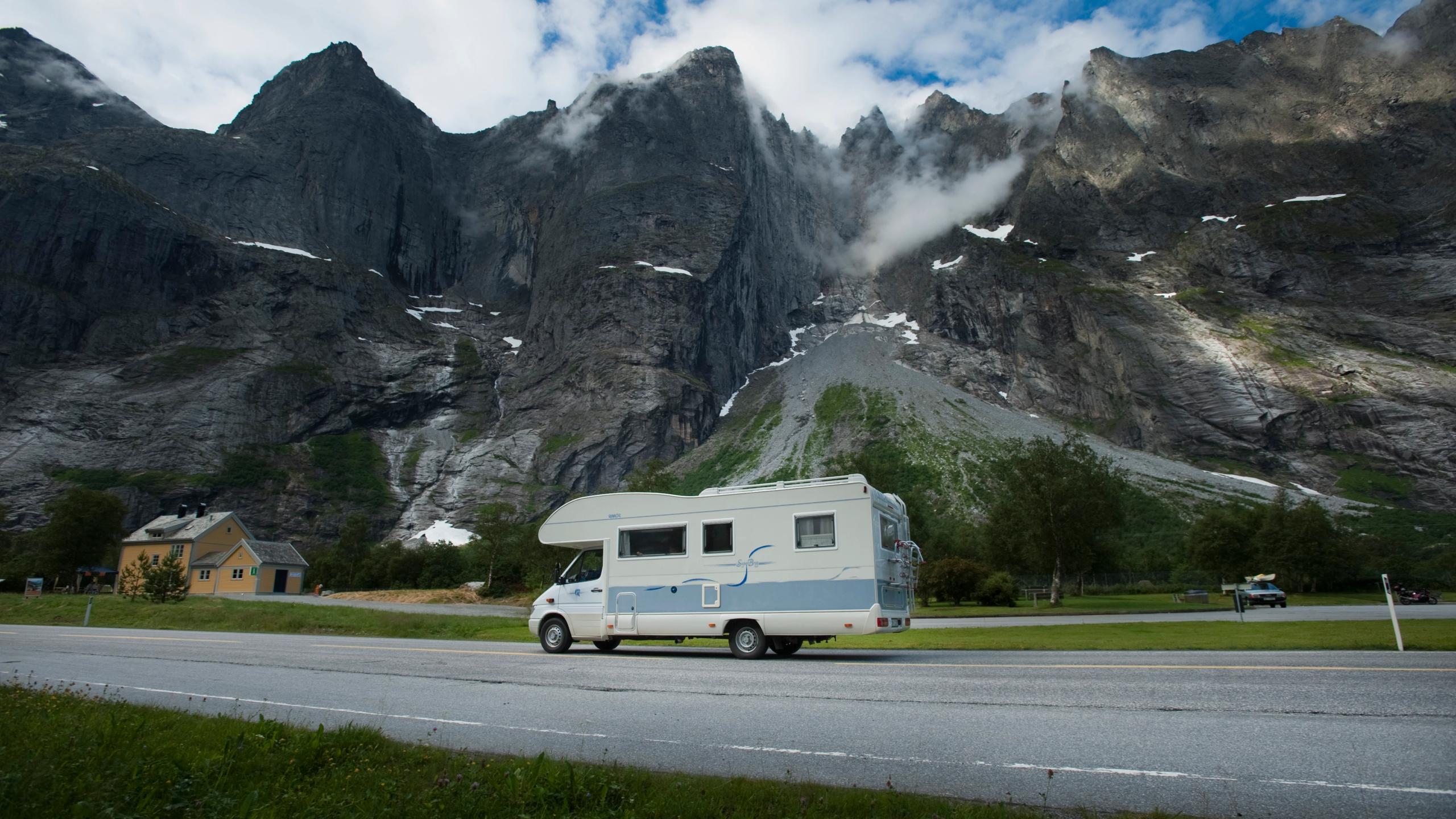 A motorhome driving on the road under the Trollveggen mountain.