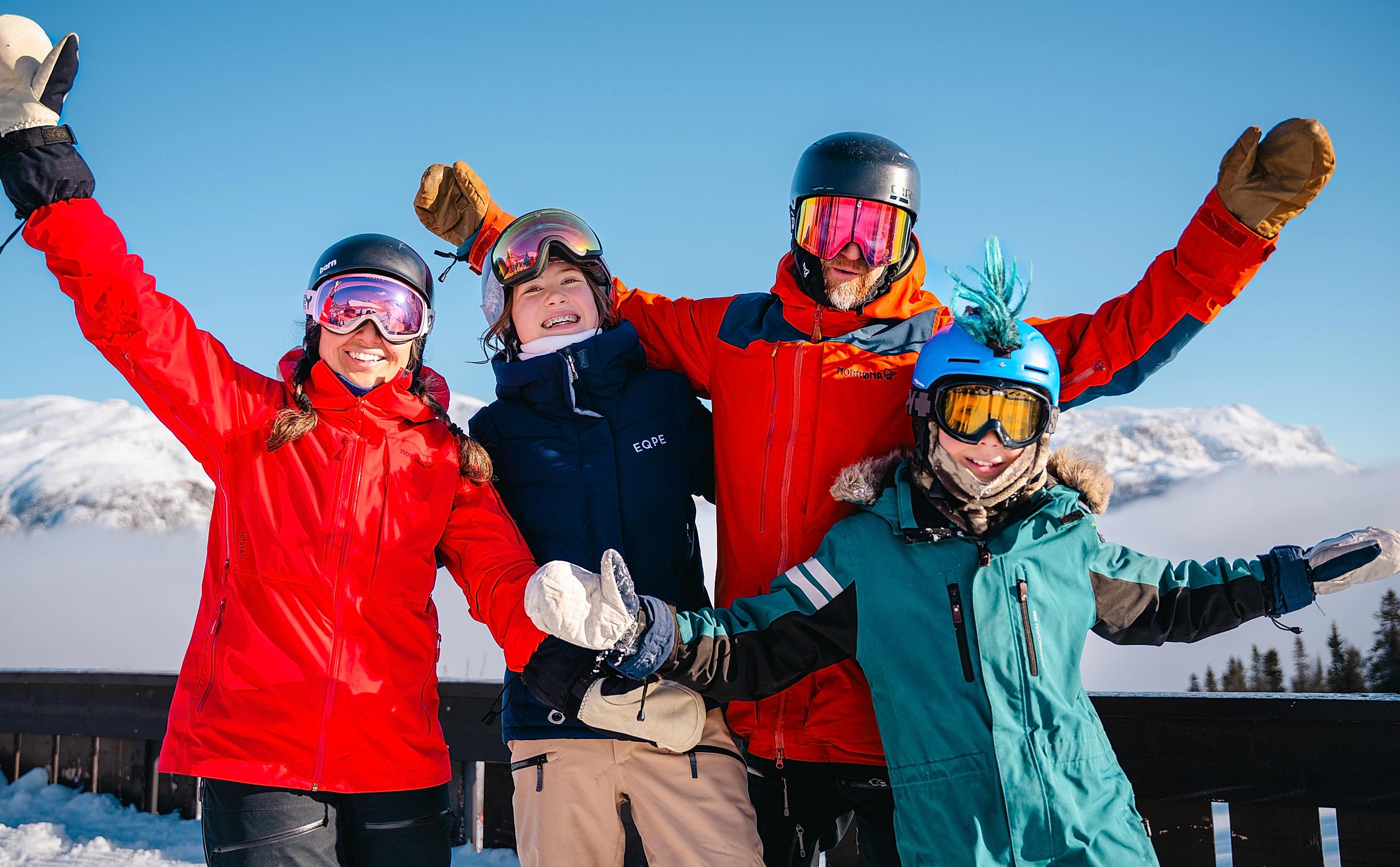 A family posing in front of a mountain at a ski resort.