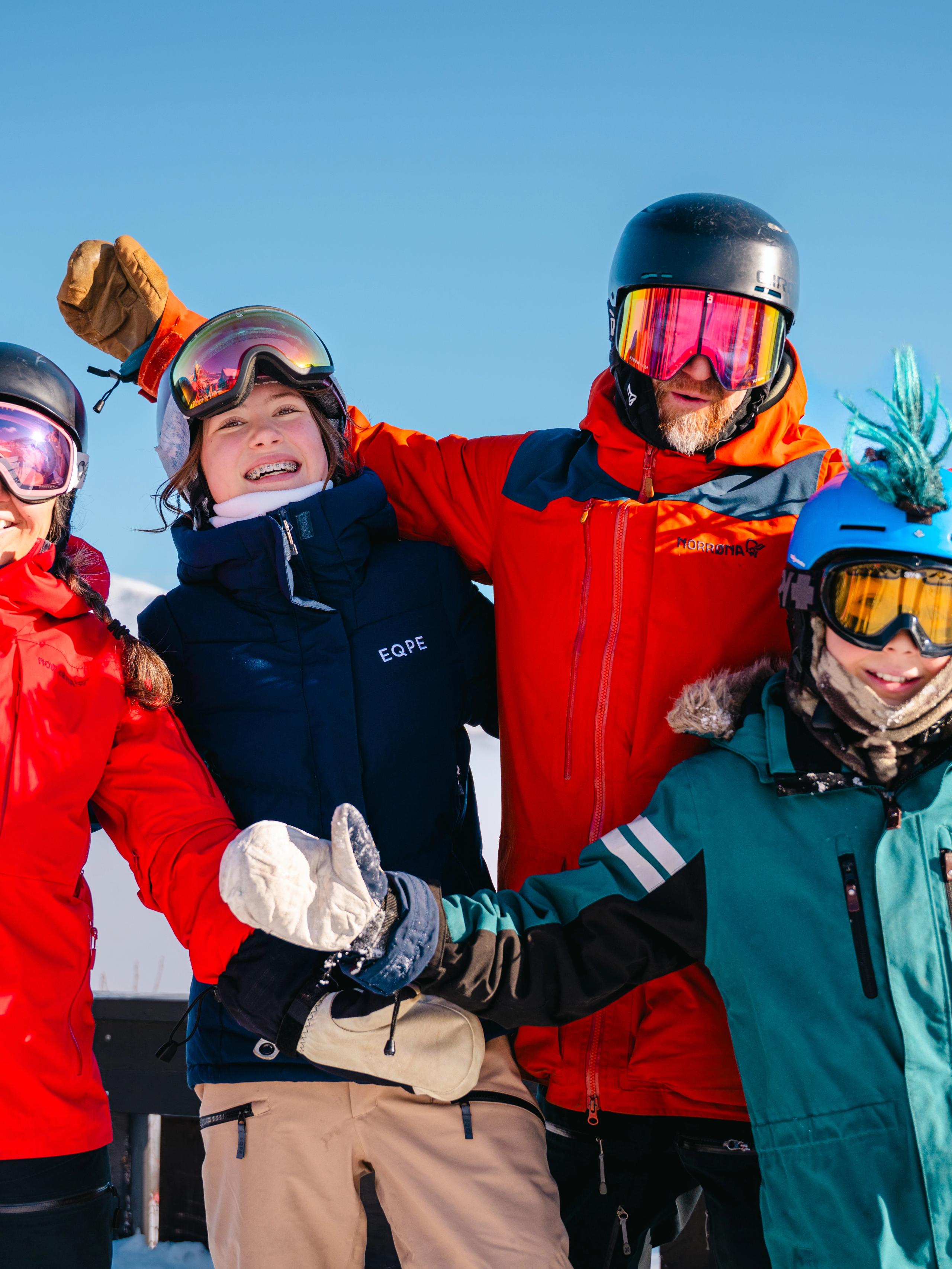 A family posing in front of a mountain at a ski resort.