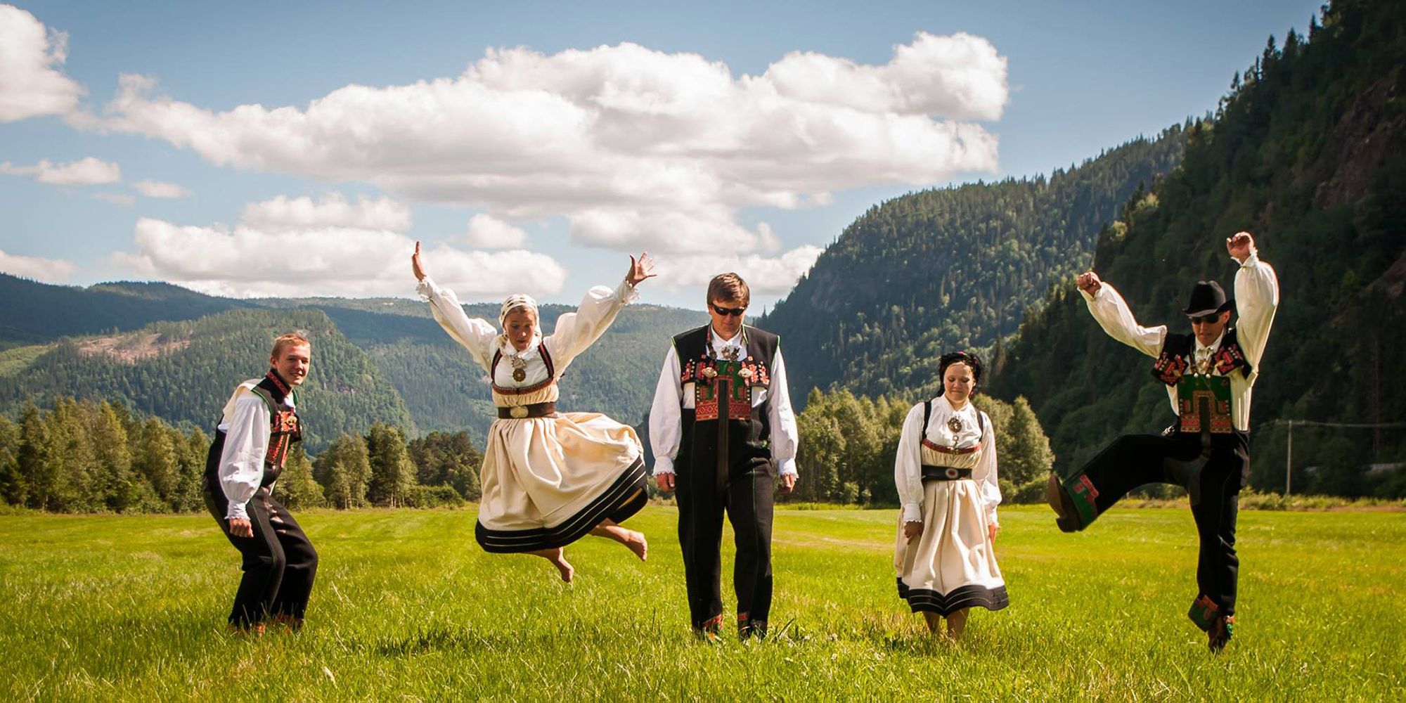 Fire mennesker i Setesdalsbunad danser i Setesdal på Sørlandet