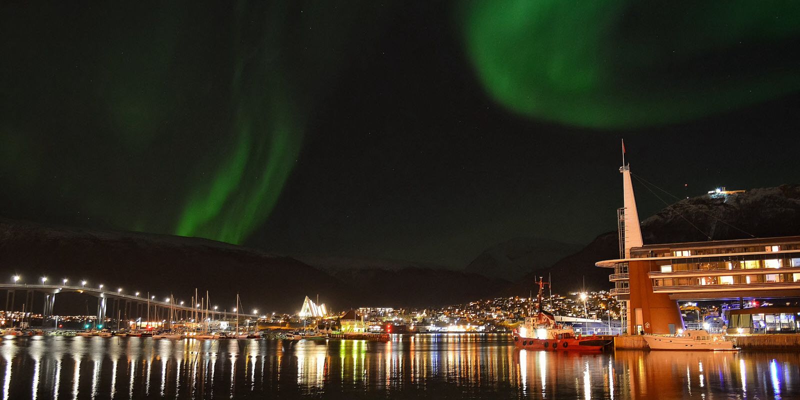 Oversiktsbilde av Tromsø og Scandic Ishavshotel under nordlys.