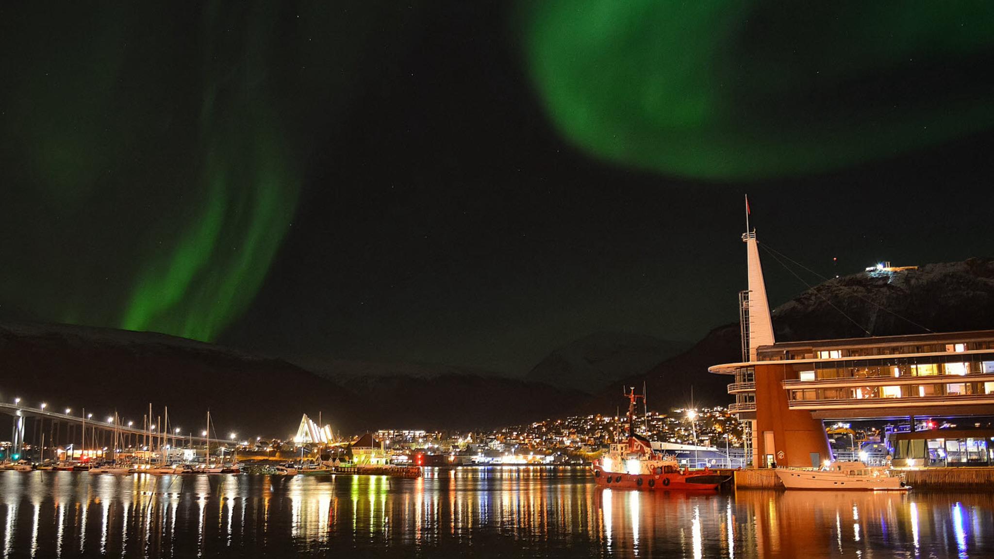 Oversiktsbilde av Tromsø og Scandic Ishavshotel under nordlys.