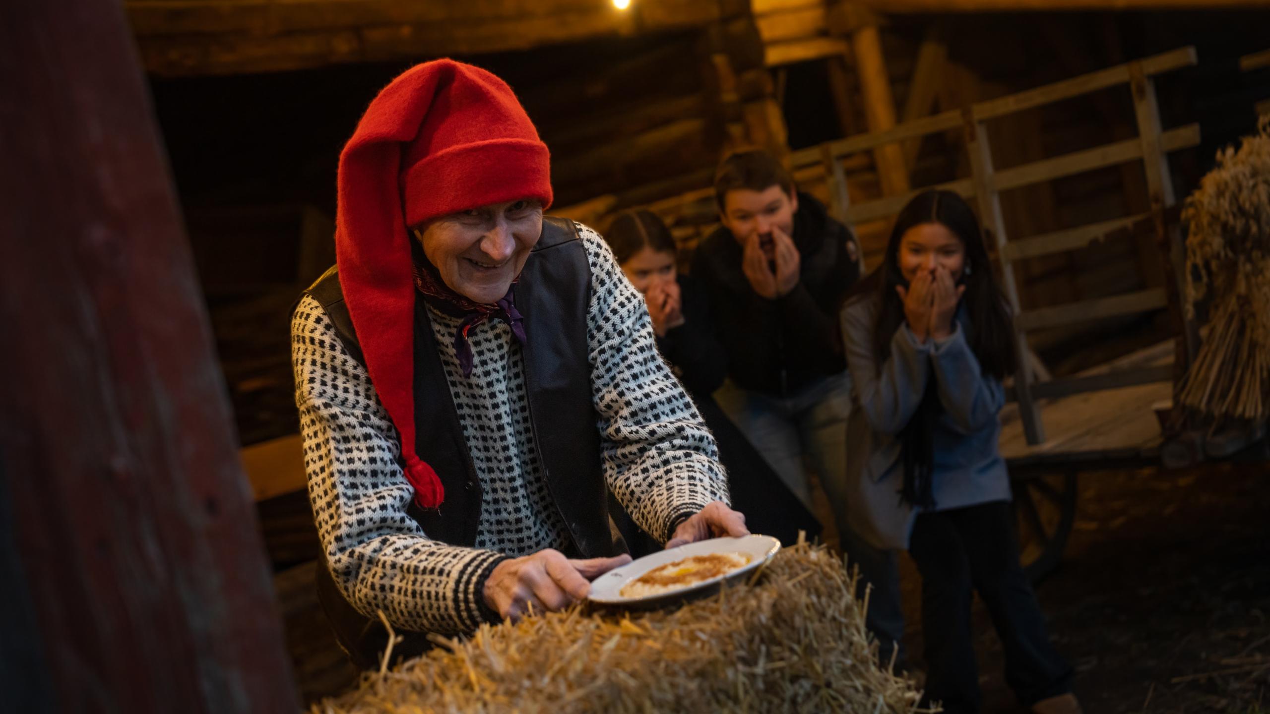 The Norwegian Santa is getting a hold of the porridge, while children is excited in the background at Bygdøy, Eastern Norway
