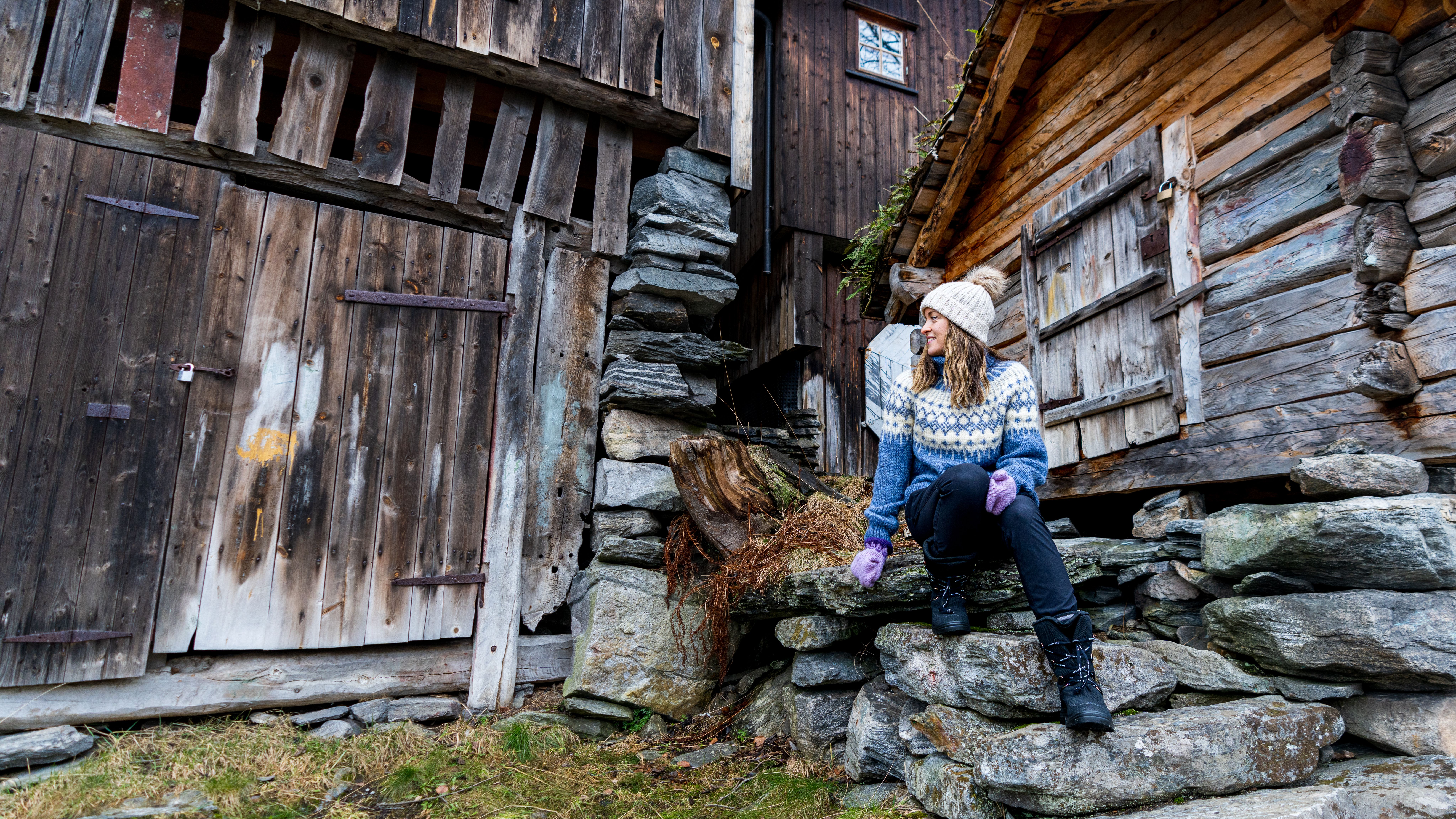 En kvinne sitter i en steintrapp i Geiranger