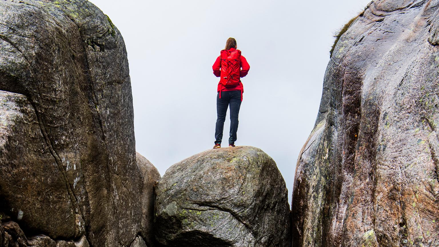 A woman standing on the famous Kjeragbolten rock on Mount Kjerag in Ryfylke, Fjord Norway