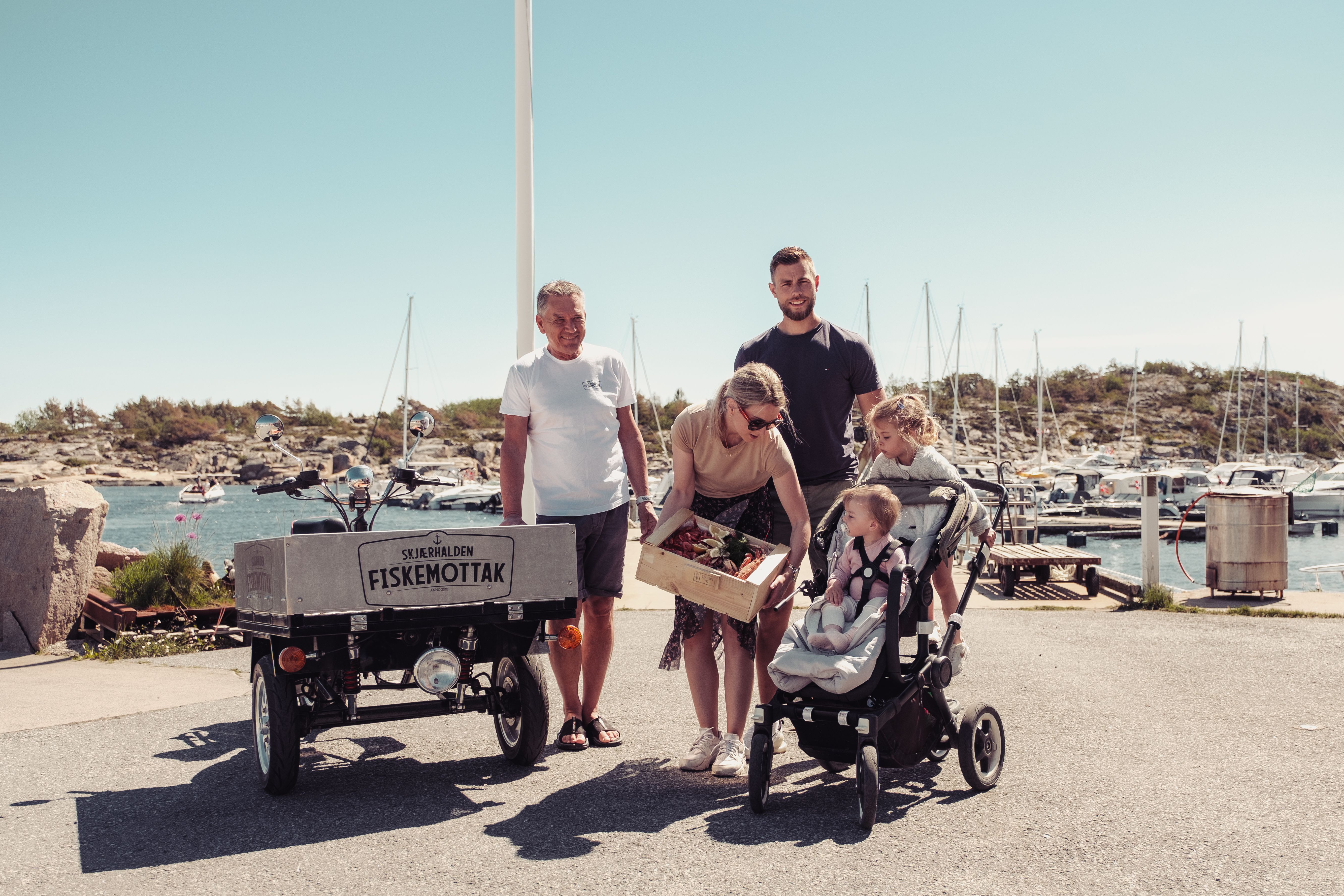 En familie kjøper en skalldyrkasse på Skjærhalden fiskemottak på Hvaler på Østlandet