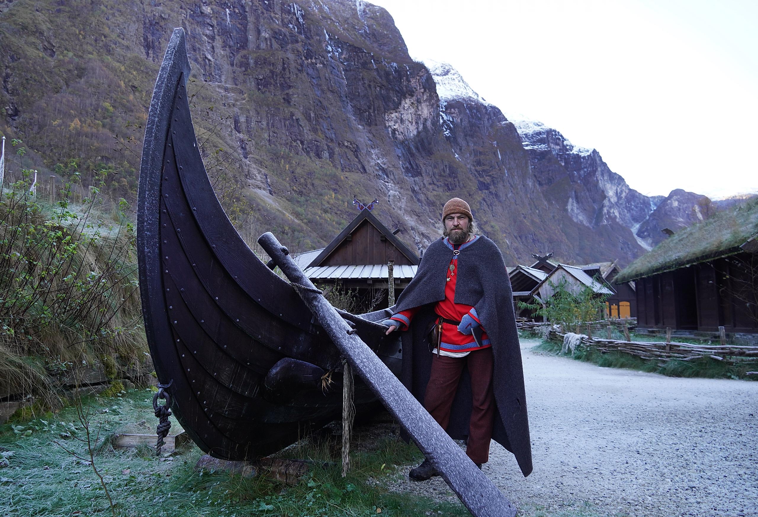 En viking foran et vikingskip i vikingbyen i Gudvangen