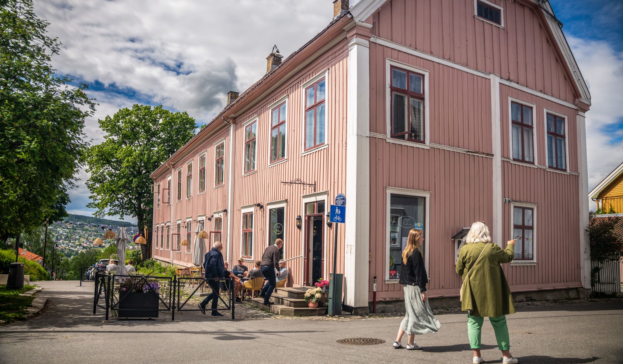 People exploring the old town of Kongsvinger next to a pink house