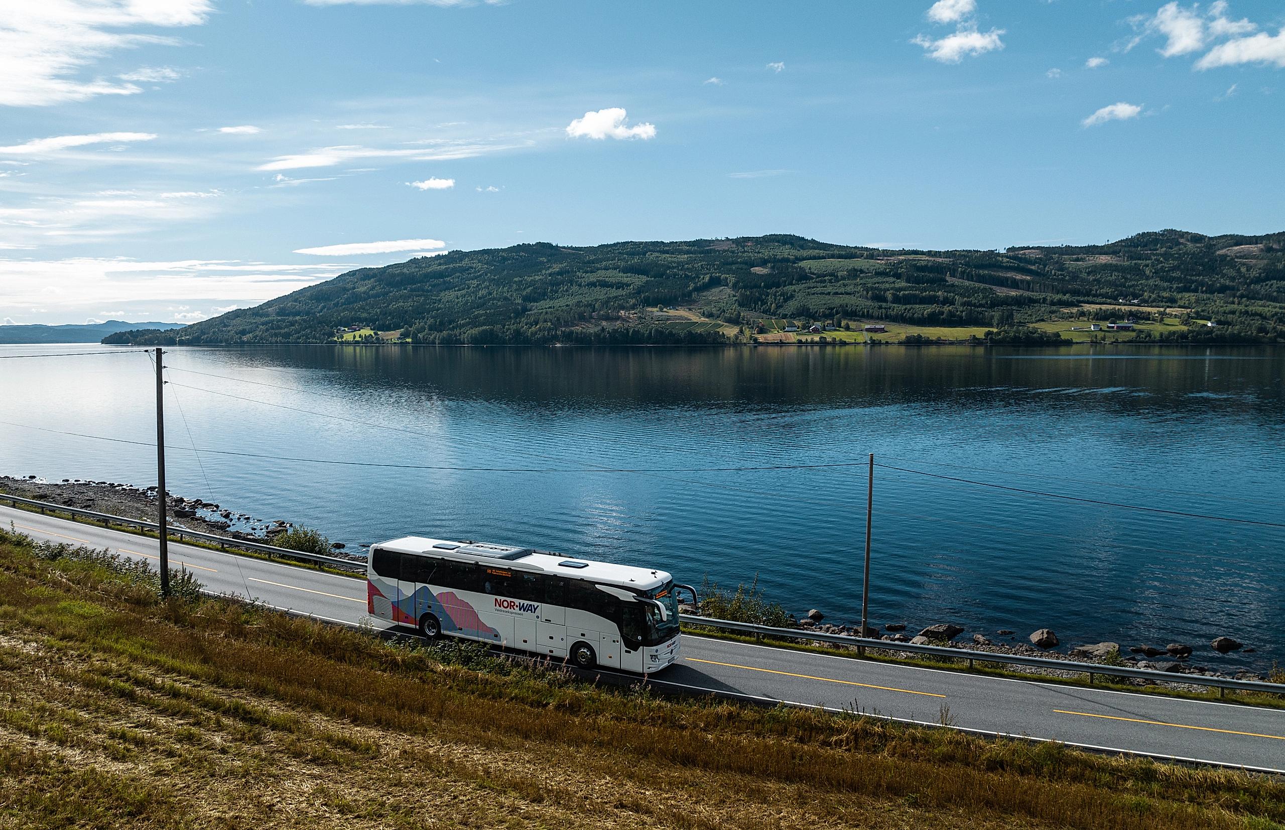 A bus from NOR-WAY Bussekspress driving along a fjord in Norway.
