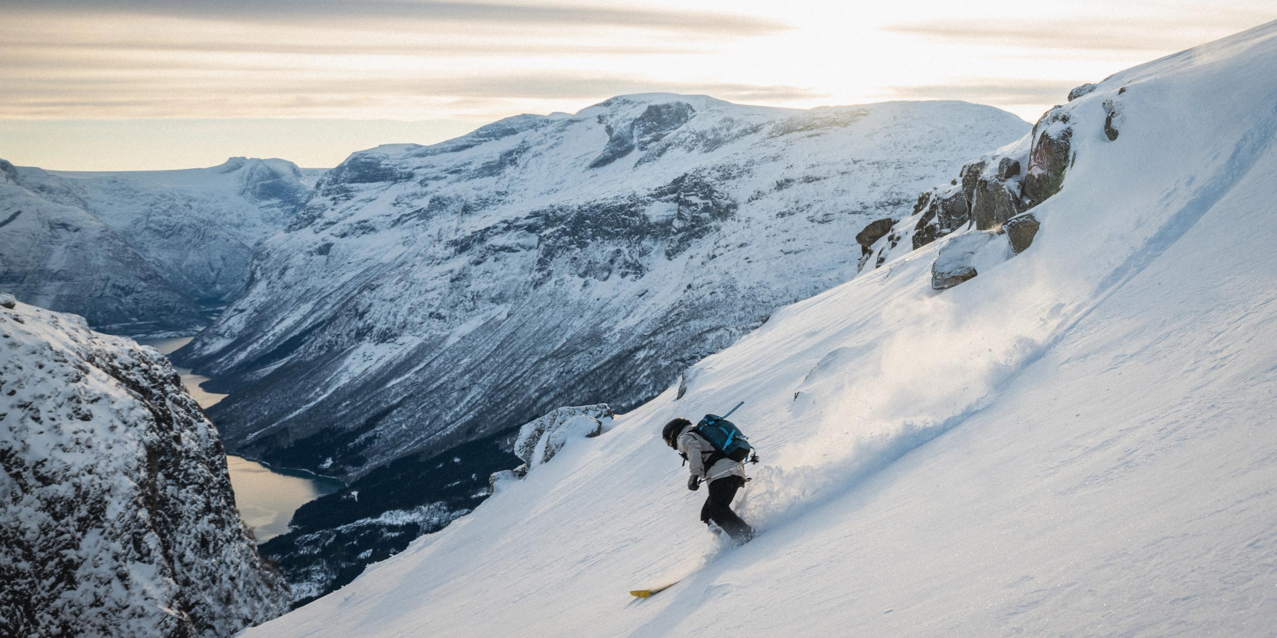 A person skiing down a mountain with a fjord view