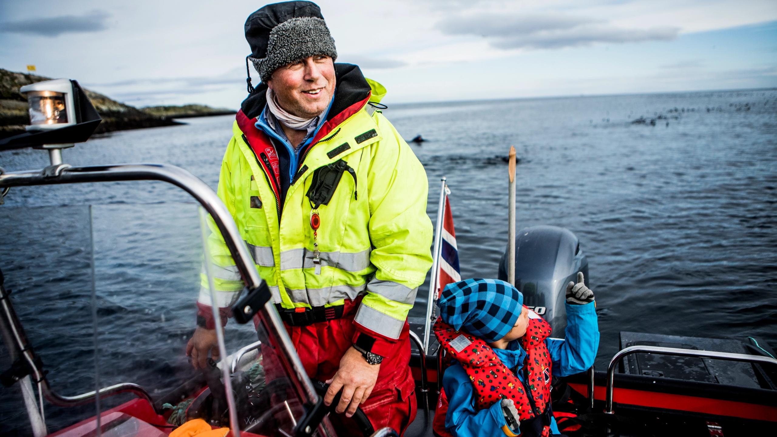 Man and boy watching birds from a boat by Hornøya