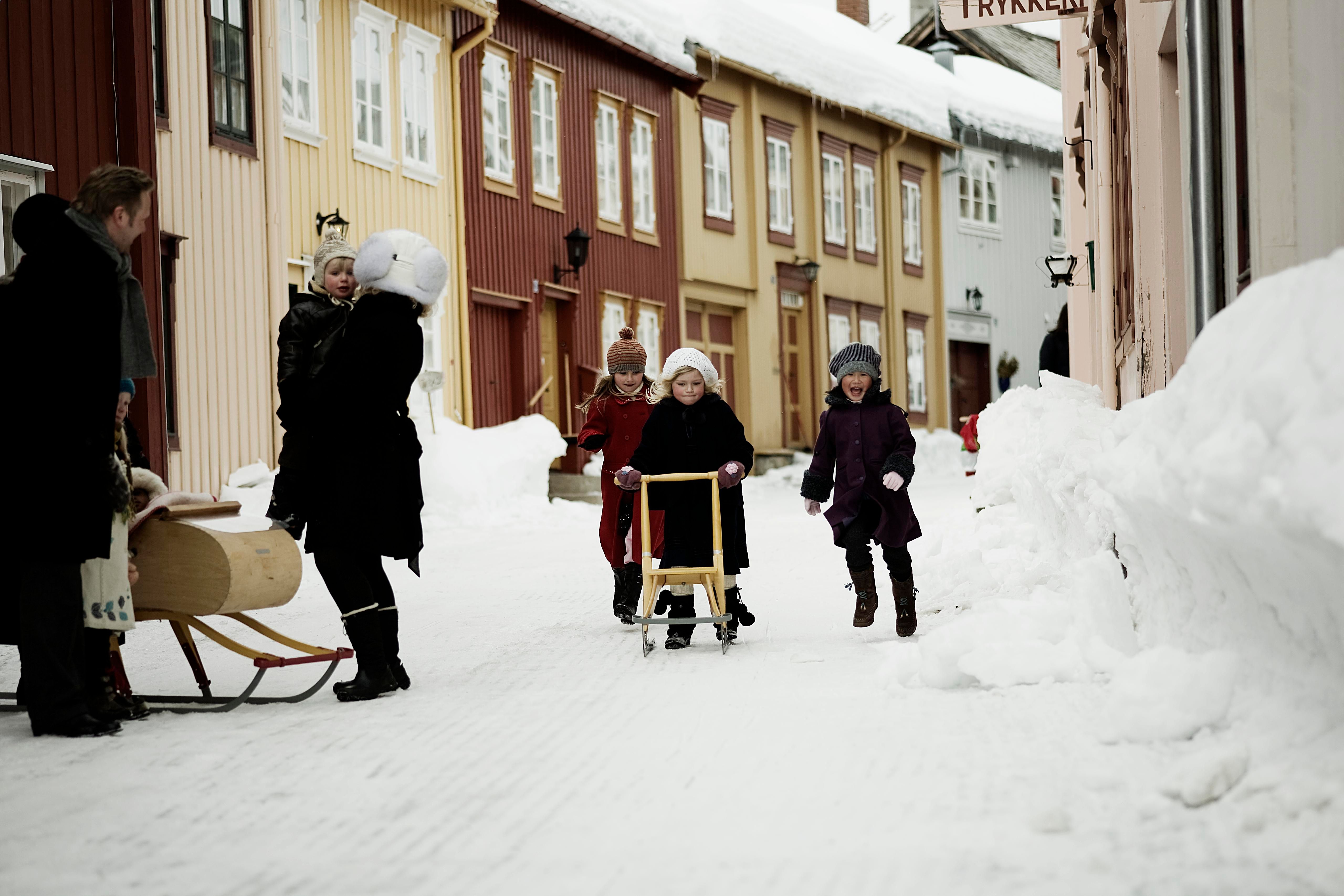 The girls are using kicksledges to move around the streets of Røros in Trøndelag during winter