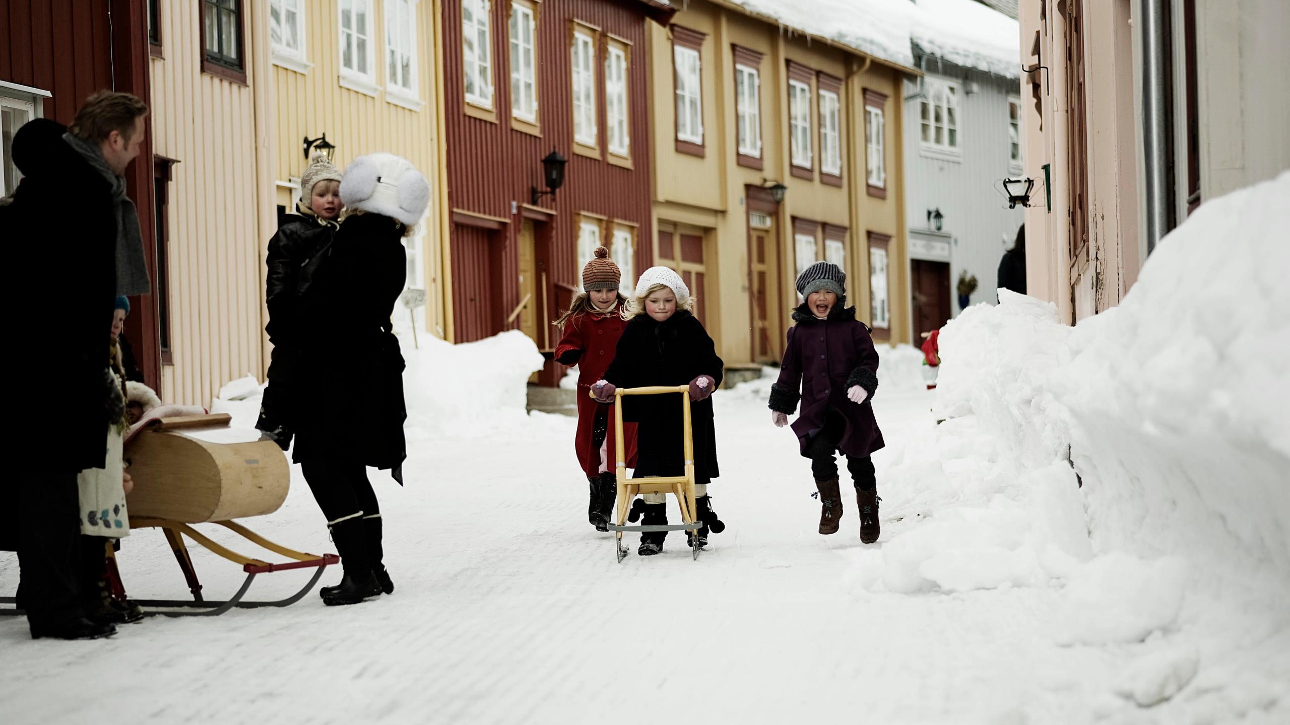 The girls are using kicksledges to move around the streets of Røros in Trøndelag during winter