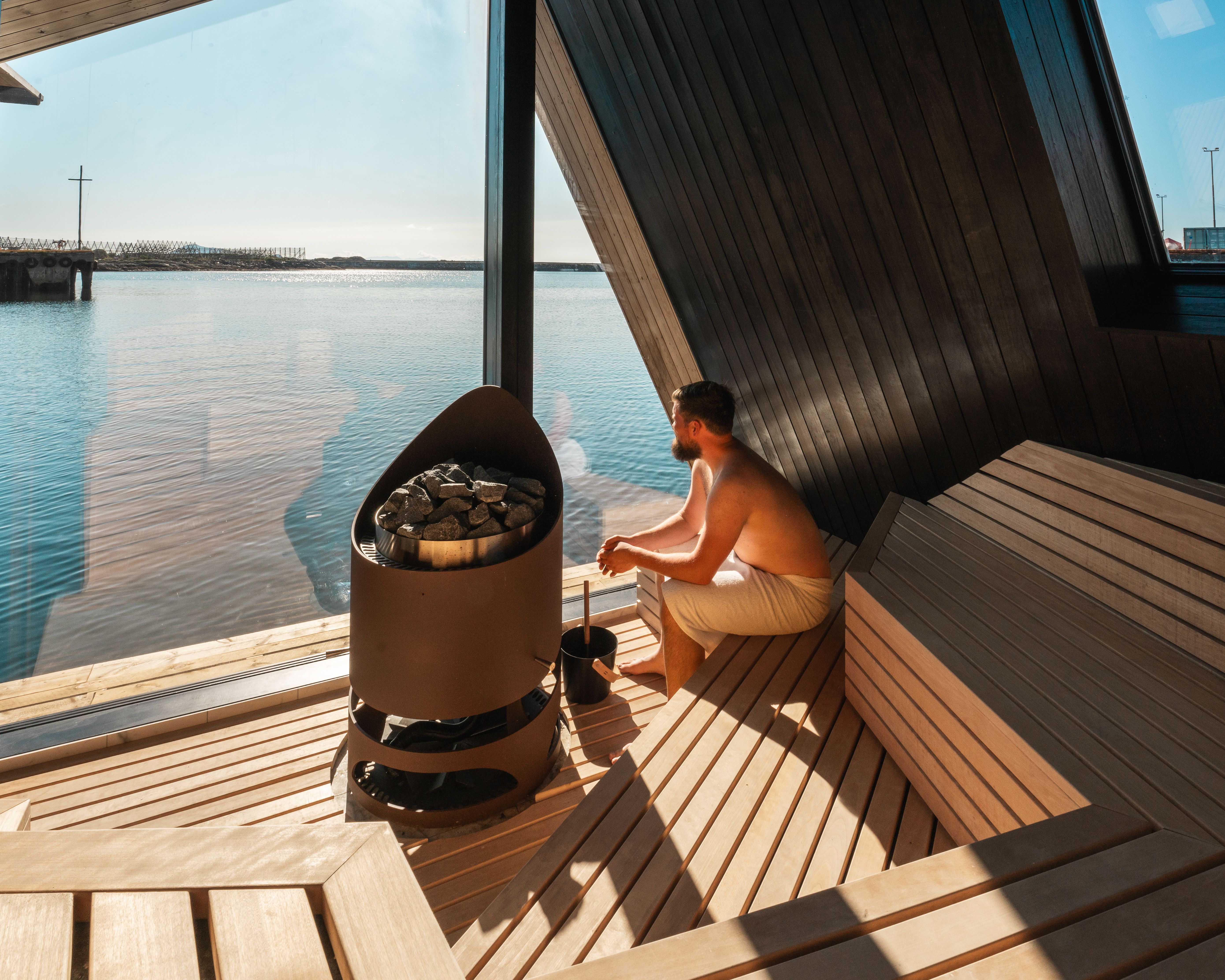 A man in a sauna looking at the view of the sea.