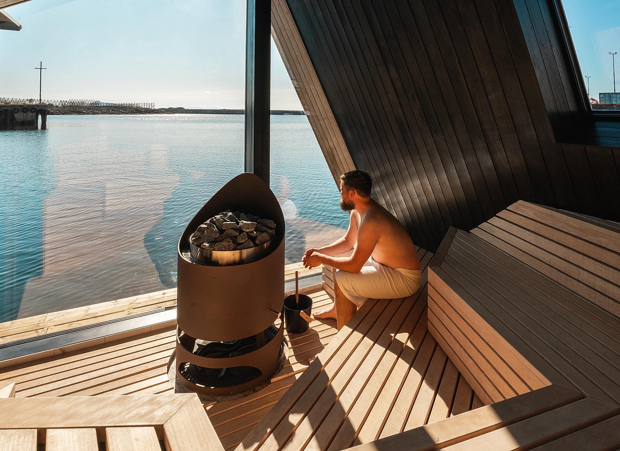 A man in a sauna looking at the view of the sea.