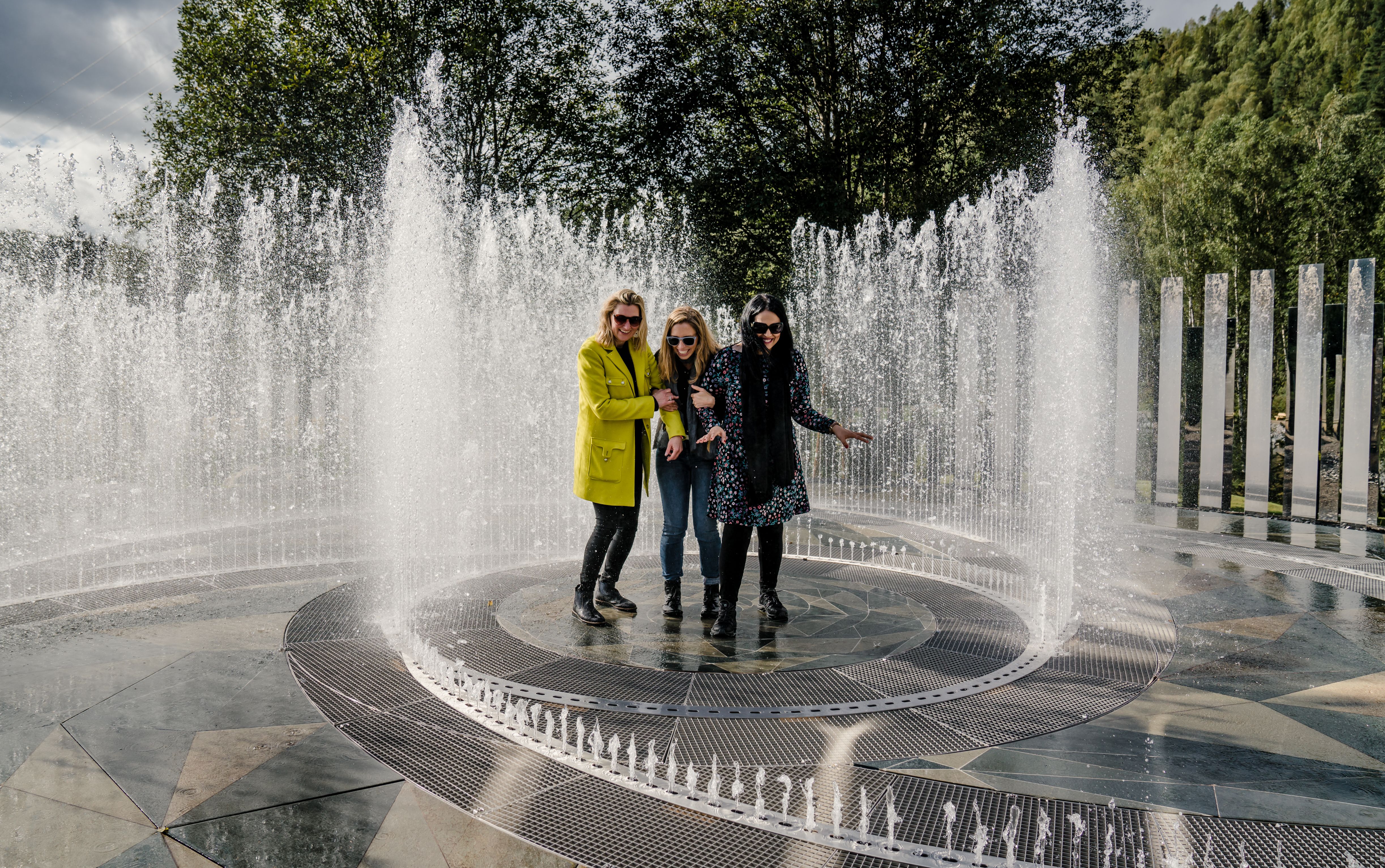 Vier Frauen stehen im Brunnen, umrundet von Spiegeln im Kistefoss Museum in Norwegen
